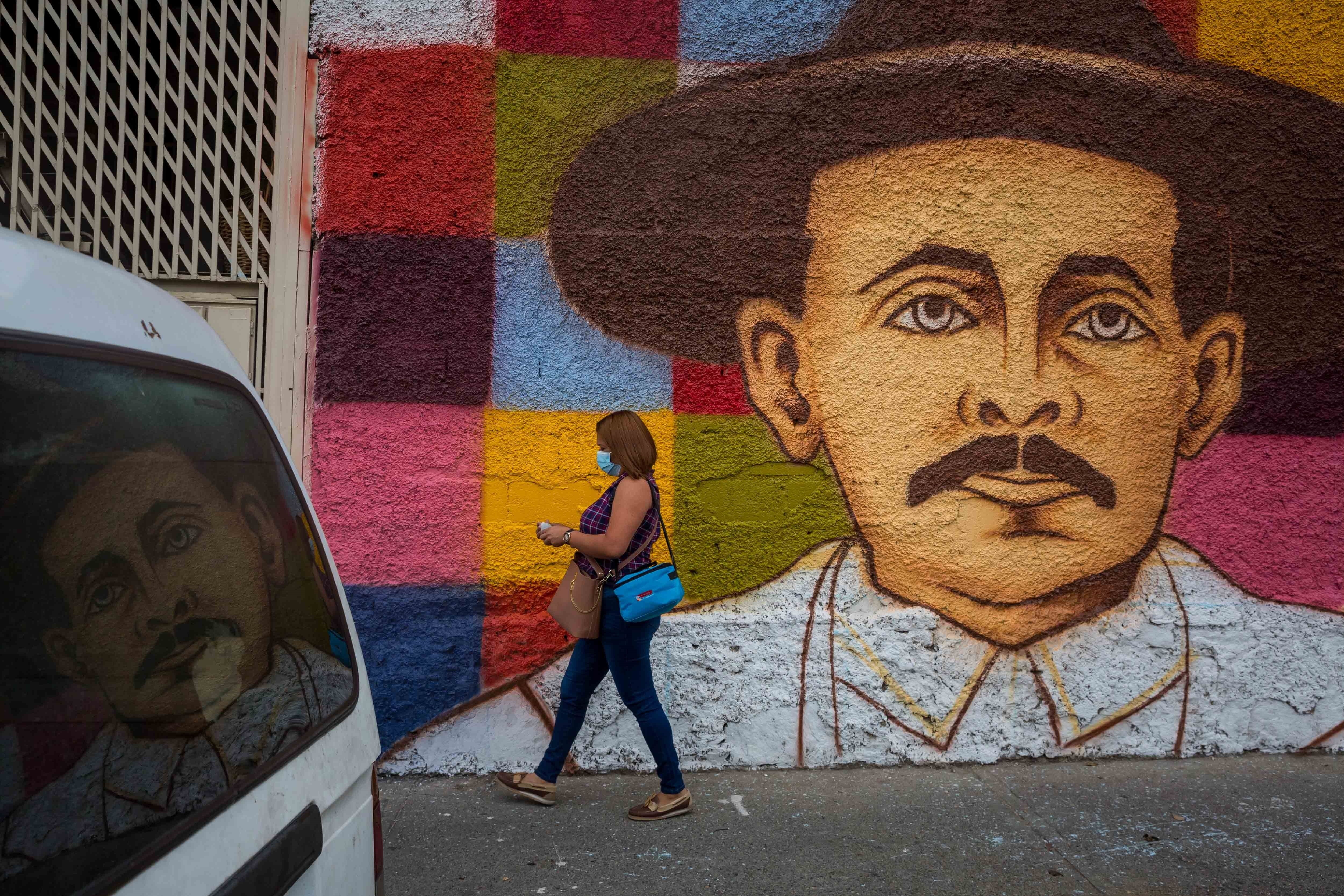 Una persona camina frente a un mural de José Gregorio Hernández, el 27 de abril de 2021, en Caracas (EFE/Miguel Gutiérrez)