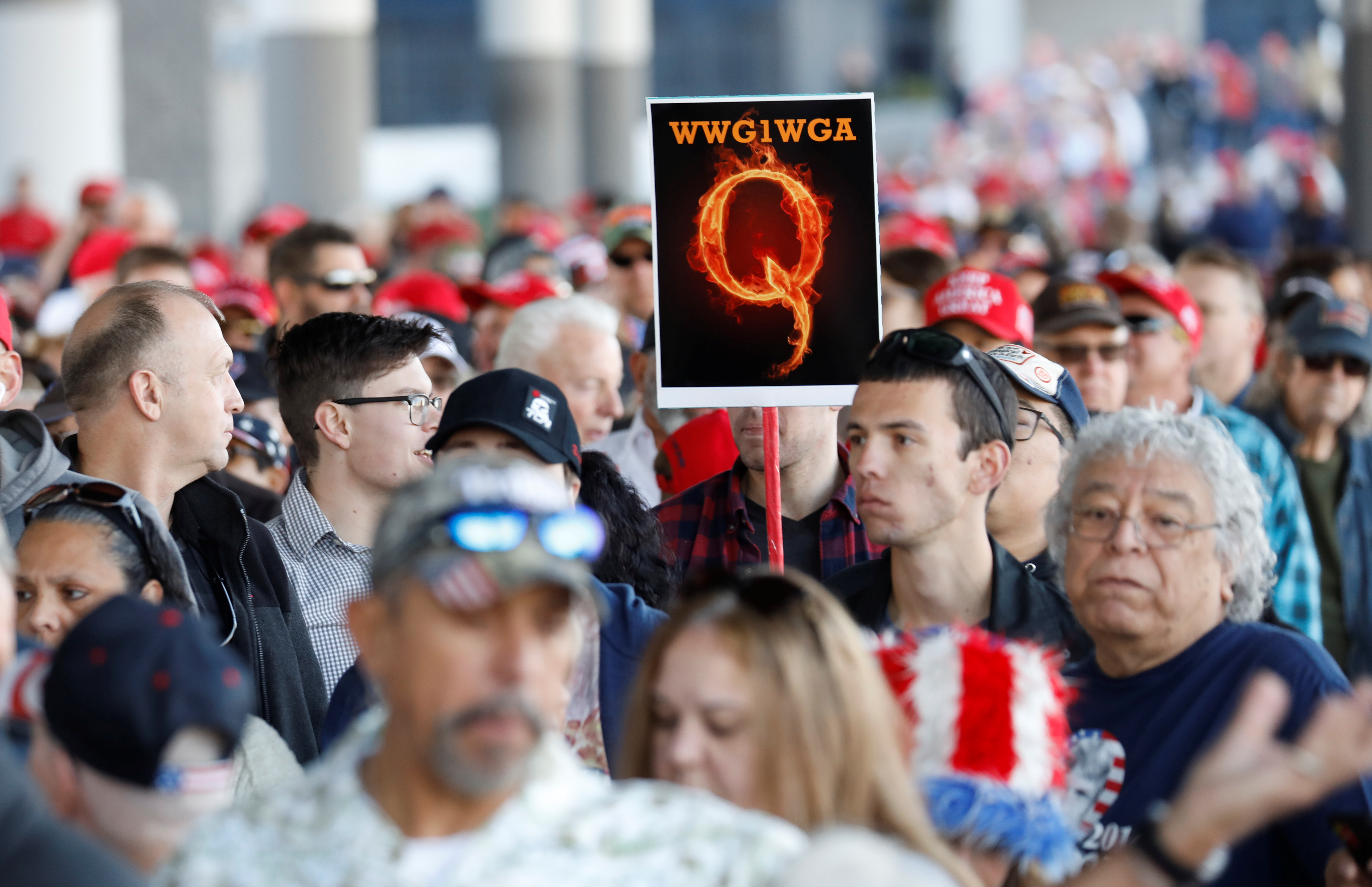 Un hombre en la multitud sostiene un cartel de QAnon con la abreviatura del grupo de su grito de reunión "Donde vamos uno, vamos todos" mientras la multitud se reúne para asistir al mitin de la campaña del Presidente de los Estados Unidos Donald Trump en el Centro de Convenciones de Las Vegas en Las Vegas, Nevada, EE.UU., el 21 de febrero de 2020 (REUTERS/Patrick Fallon)