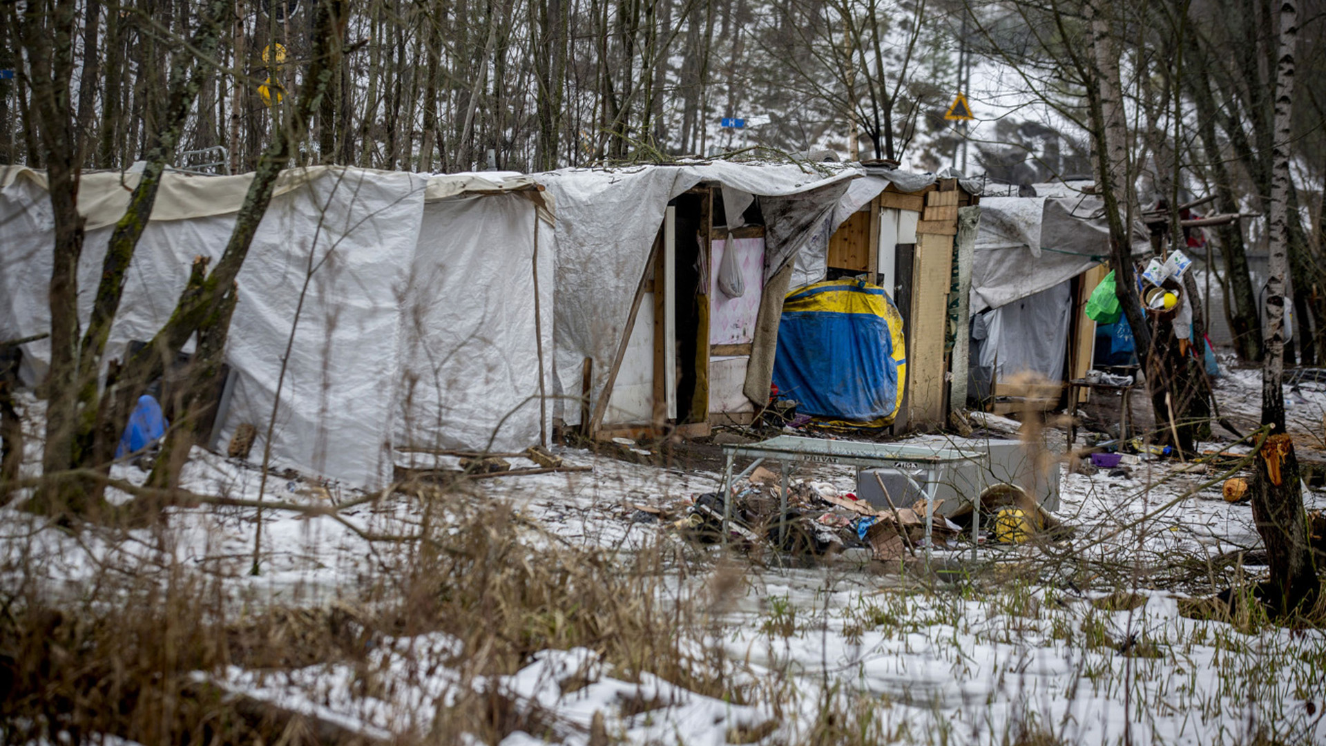 Un tren de pasajeros pasa por delante de los refugios improvisados de los migrantes en un campamento temporal en una ladera boscosa de Estocolmo, Suecia, en febrero de 2014 (Fotógrafo: Casper Hedberg/Bloomberg)