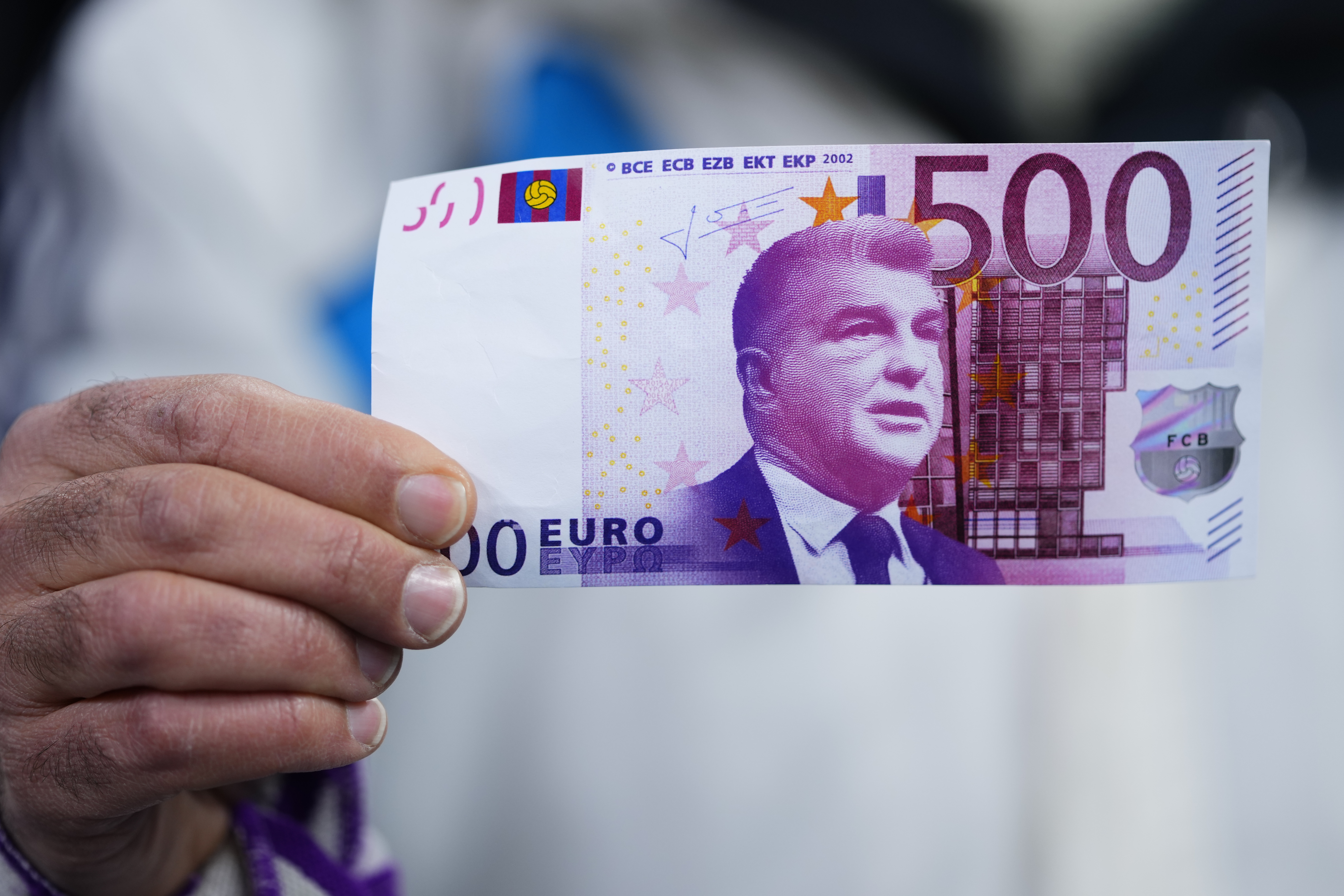 A fan holds a fake bill with the image of Joan Laporta in the preview of the Cup match between Real Madrid and Barcelona.  (AP)