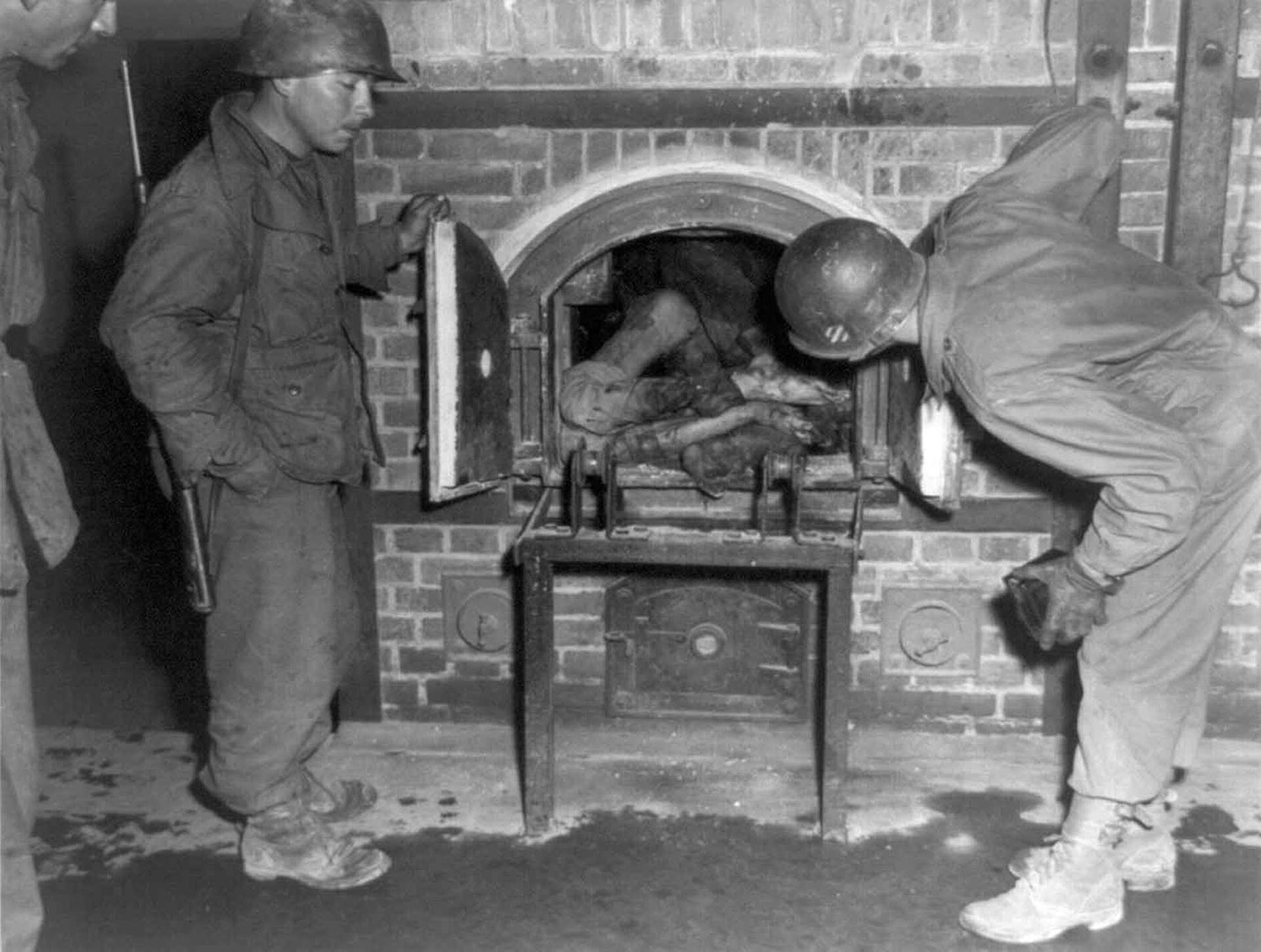 Horrorizados, tres soldados estadounidenses miran cuerpos metidos en un horno en un crematorio de Dachau en abril de 1945 (CBW)
