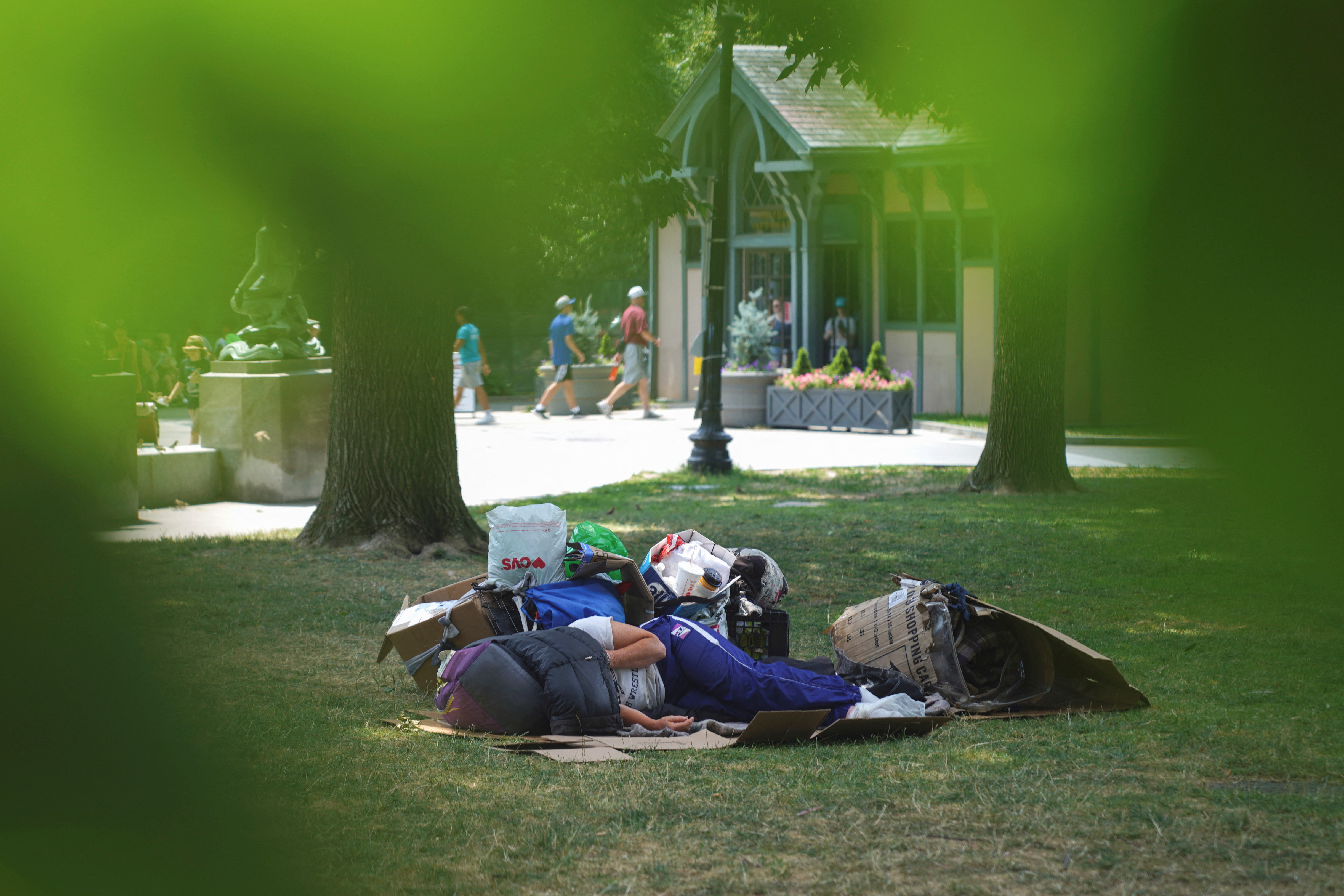 Una persona sin hogar yace en el parque con la cabeza cubierta, durante una ola de calor en Boston (REUTERS/Allison Dinner)