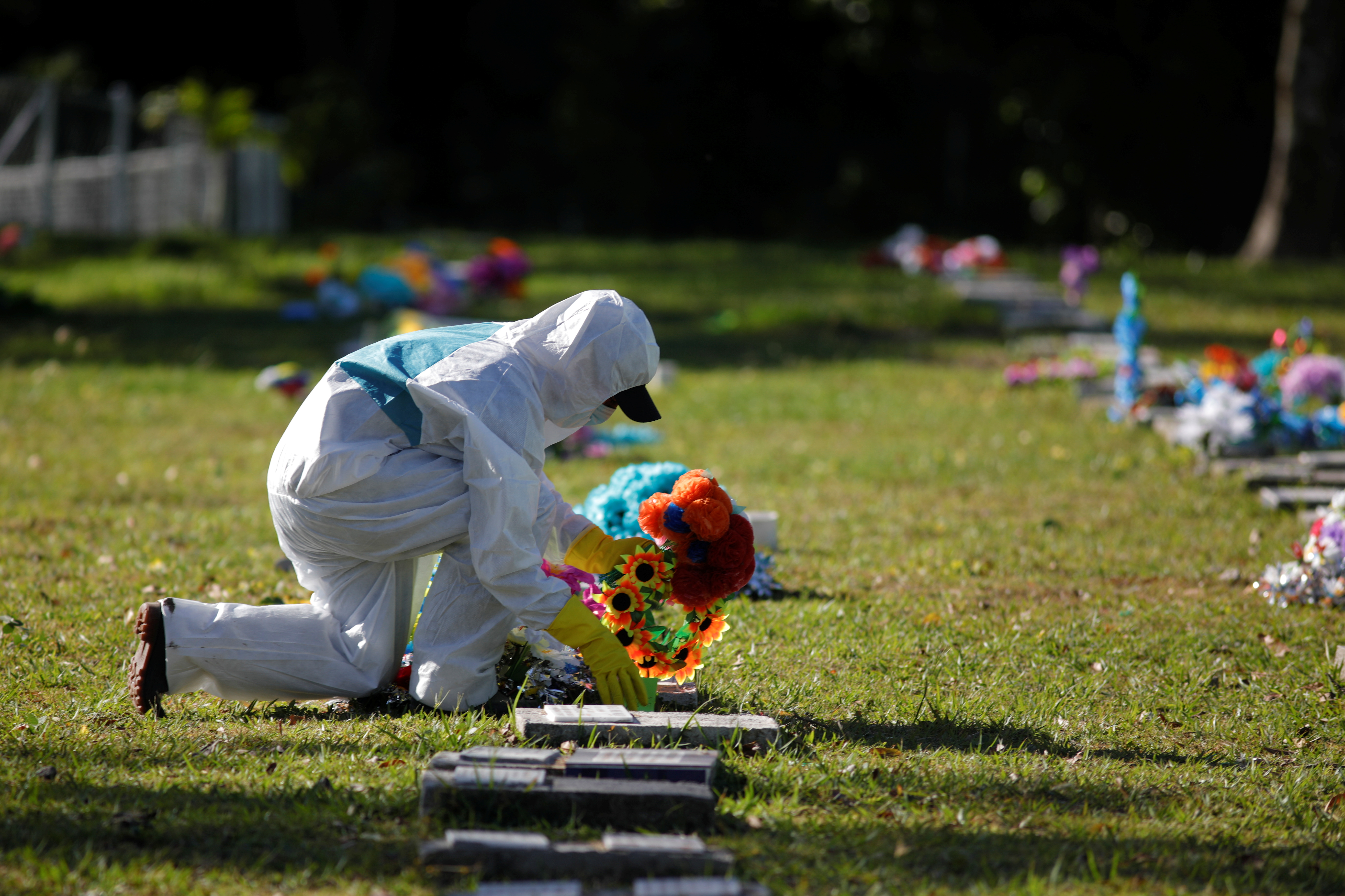 Un trabajador del cementerio pone flores en la tumba de una persona, que murió de la enfermedad del coronavirus (COVID-19),durante la celebración del Día de los Muertos, en el cementerio de La Bermeja en San Salvador, El Salvador 2 de noviembre de 2021. REUTERS/Jose Cabezas