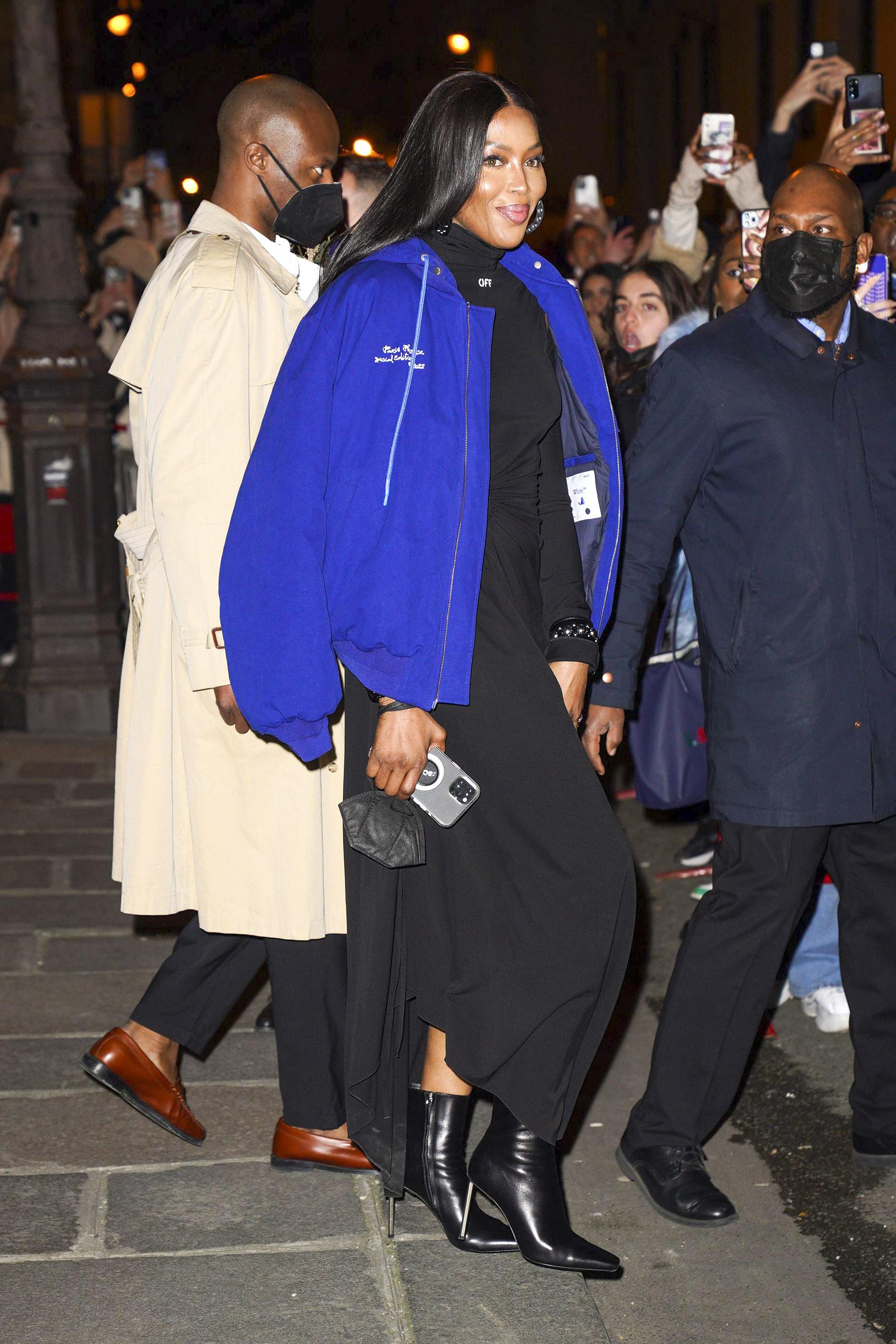 Naomi Campbell viajó a Francia para asistir a la Semana de la Moda en París. Para ello, lució un vestido negro que combinó con sus botas de cuero. Además, llevó una campera oversize azul sobre sus hombros