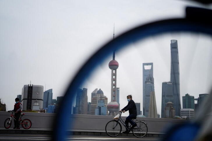 Un hombre con mascarilla pasa en bicicleta por una puente frente a la zona de Pudong (REUTERS/Aly Song)