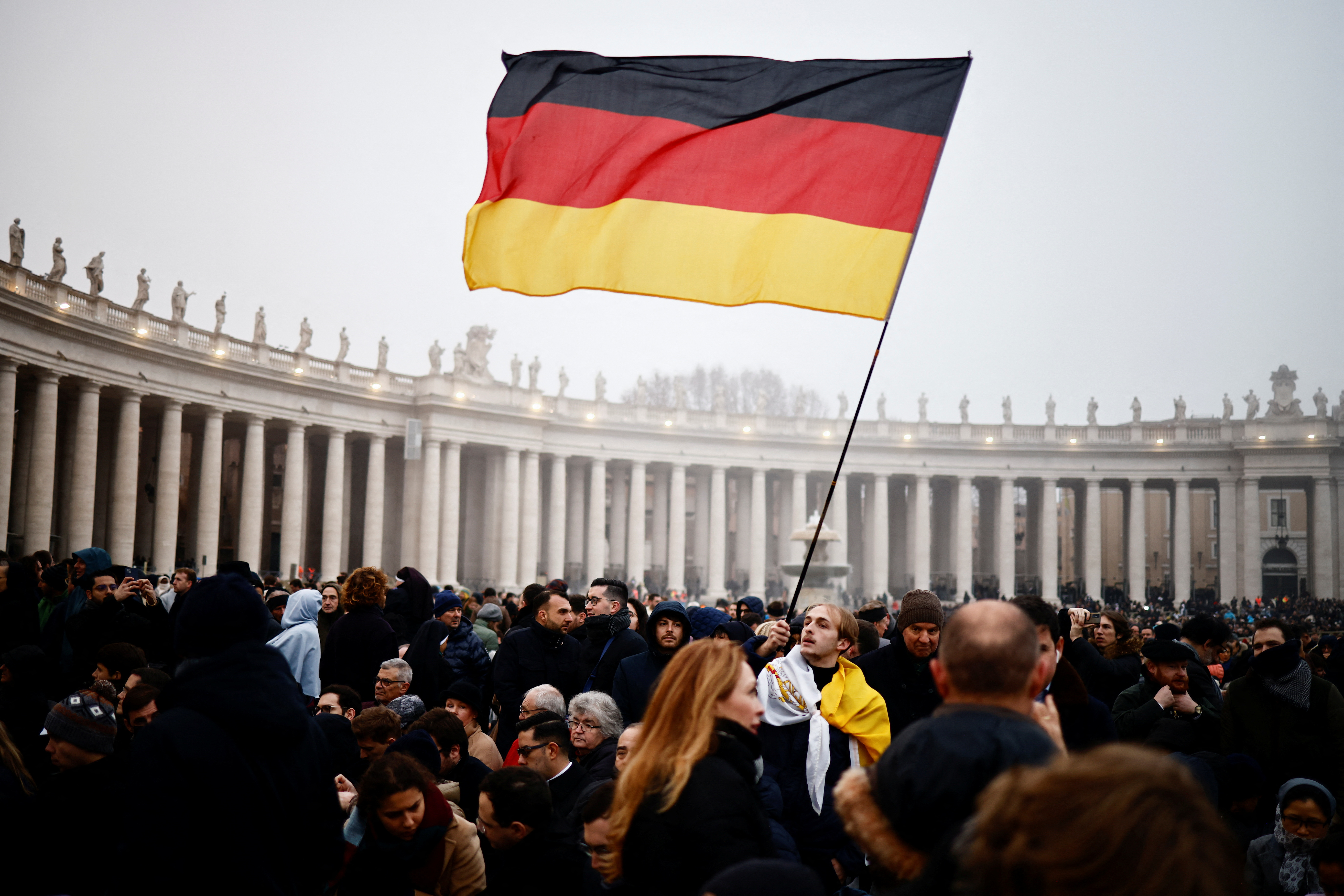 Un hombre sostiene una bandera de Alemania en la Plaza de San Pedro el día del funeral del ex Papa Benedicto XVI en el Vaticano.
