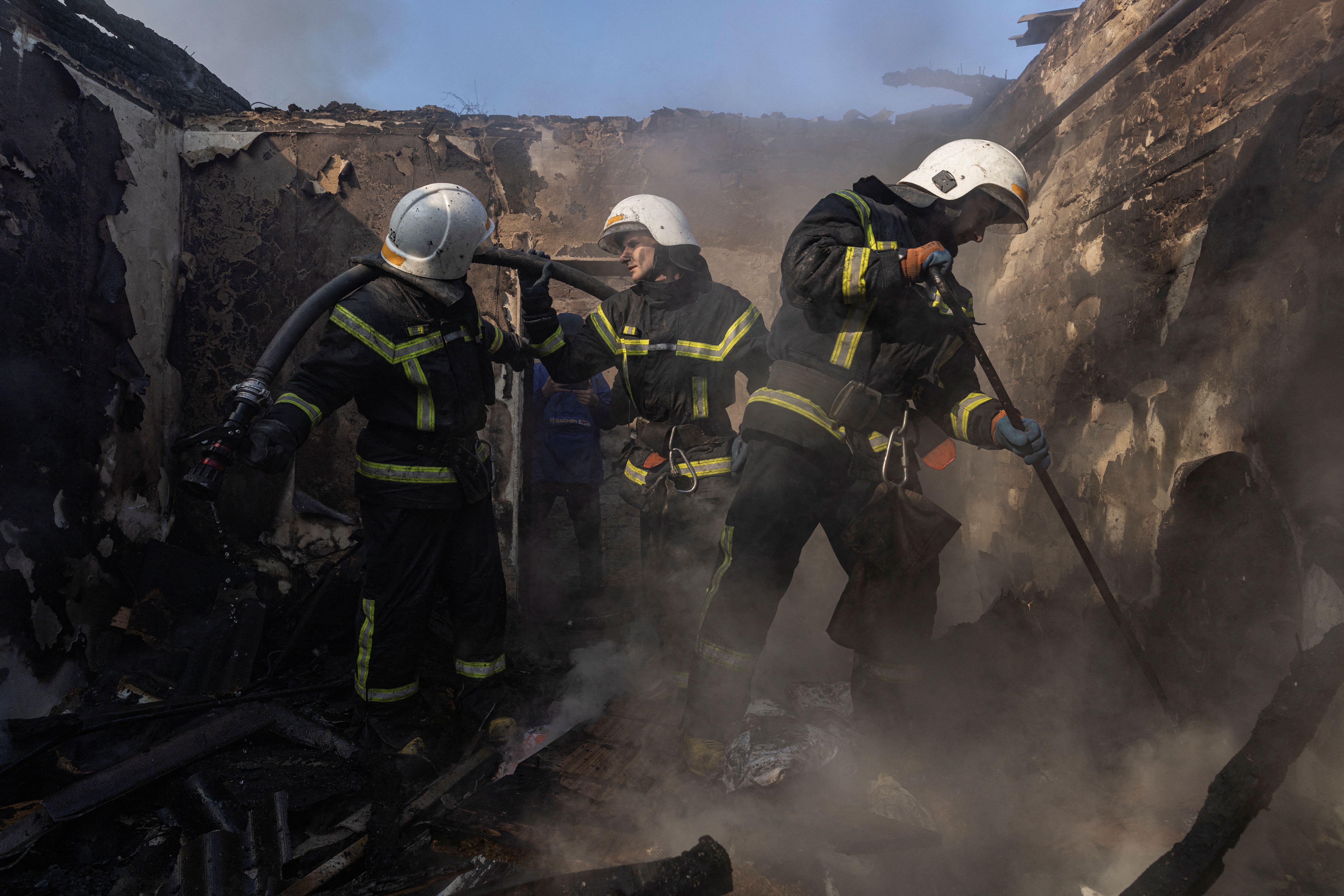 Los bomberos trabajan en un distrito residencial que resultó dañado por los bombardeos en Kiev, Ucrania, el 23 de marzo de 2022. (REUTERS/Marko Djurica)