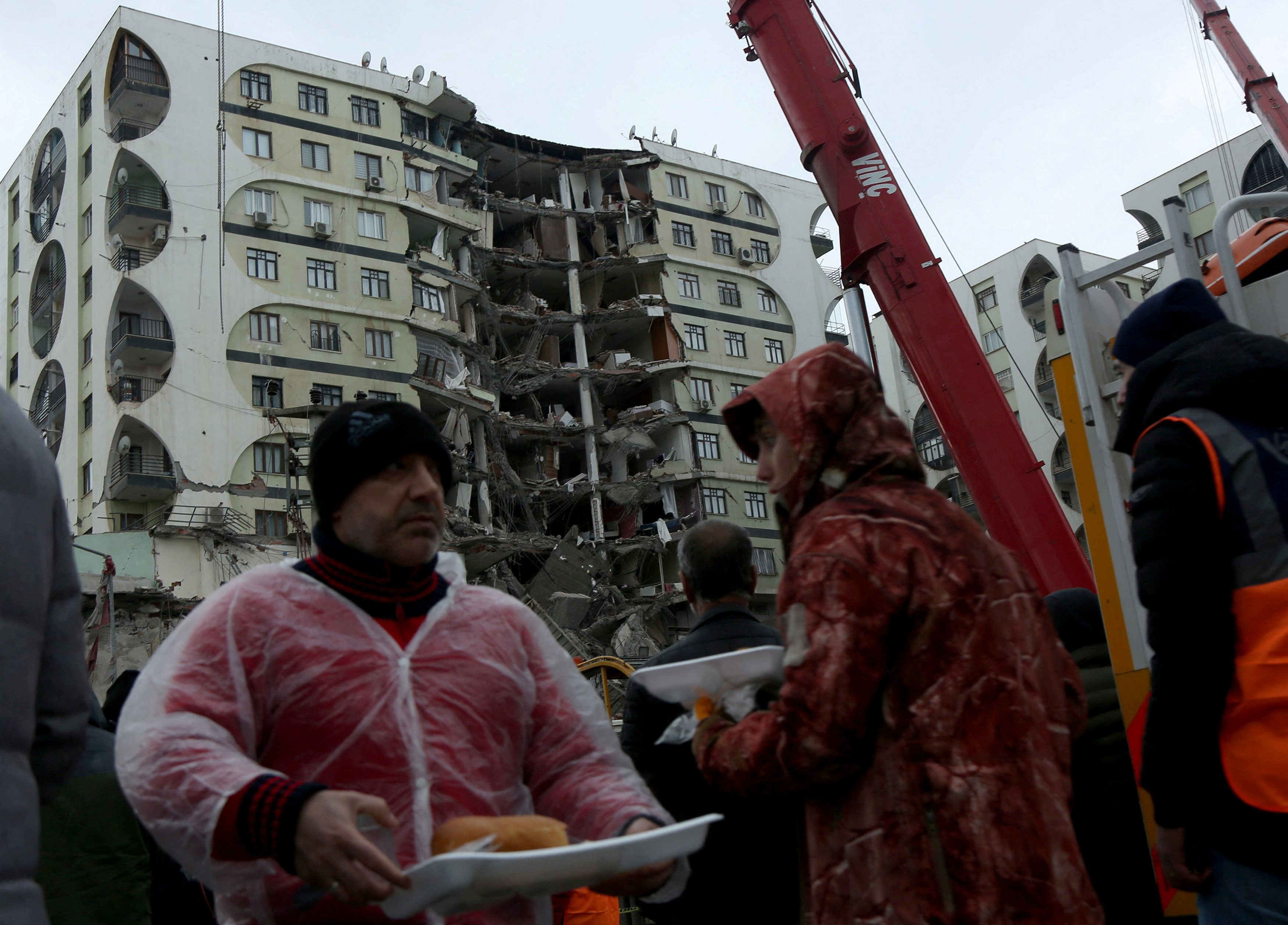 Las personas reciben alimentos mientras esperan cerca de un edificio dañado tras un terremoto en Diyarbakir, Turquía.
