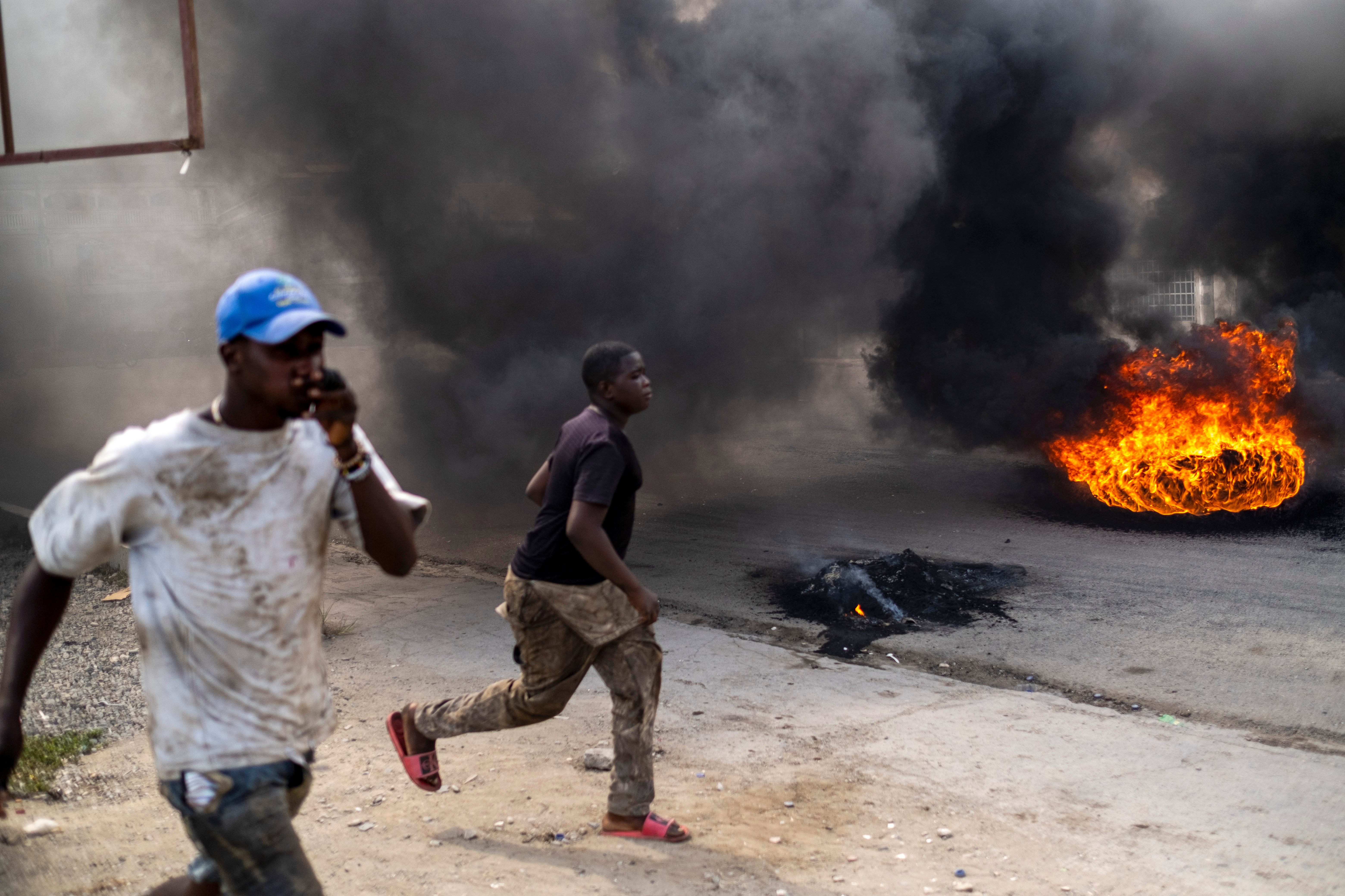 Manifestantes corren en una calle llena de humo de neumáticos quemados durante una protesta contra el asesinato del presidente Moise en Cap-Haitien, el 22 de julio de 2021 (REUTERS/Ricardo Arduengo)