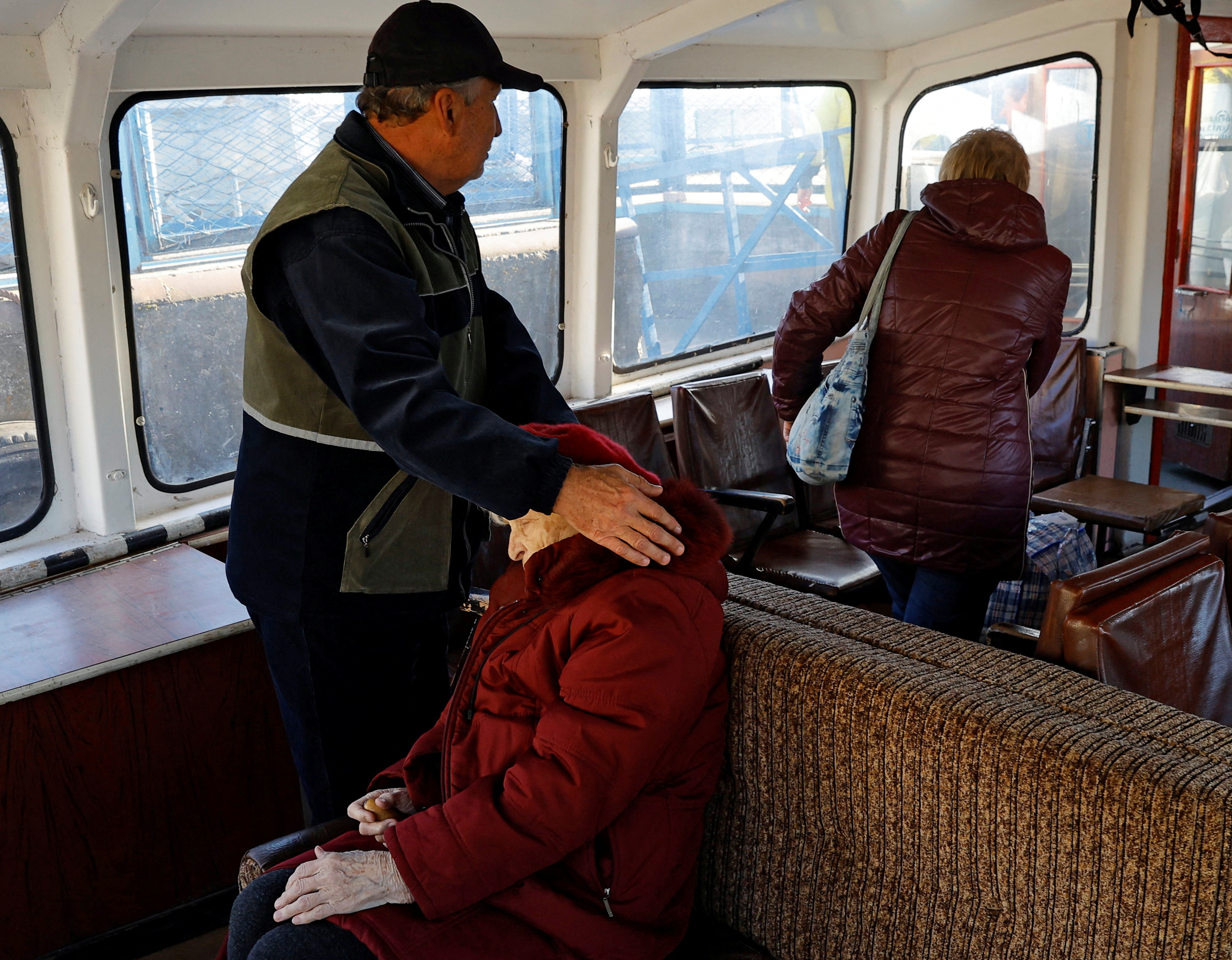 Un hombre consuela a una anciana mientras suben a un ferry durante la evacuación de los residentes de Kherson, el 31 de octubre de 2022. REUTERS/Alexander Ermochenko