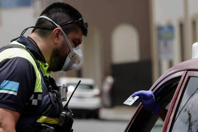 Un oficial de policía realiza un control de identidad a los ocupantes de un automóvil, siguiendo las restricciones del gobierno de Costa Rica para prevenir el brote de coronavirus (COVID-19), en San José. 