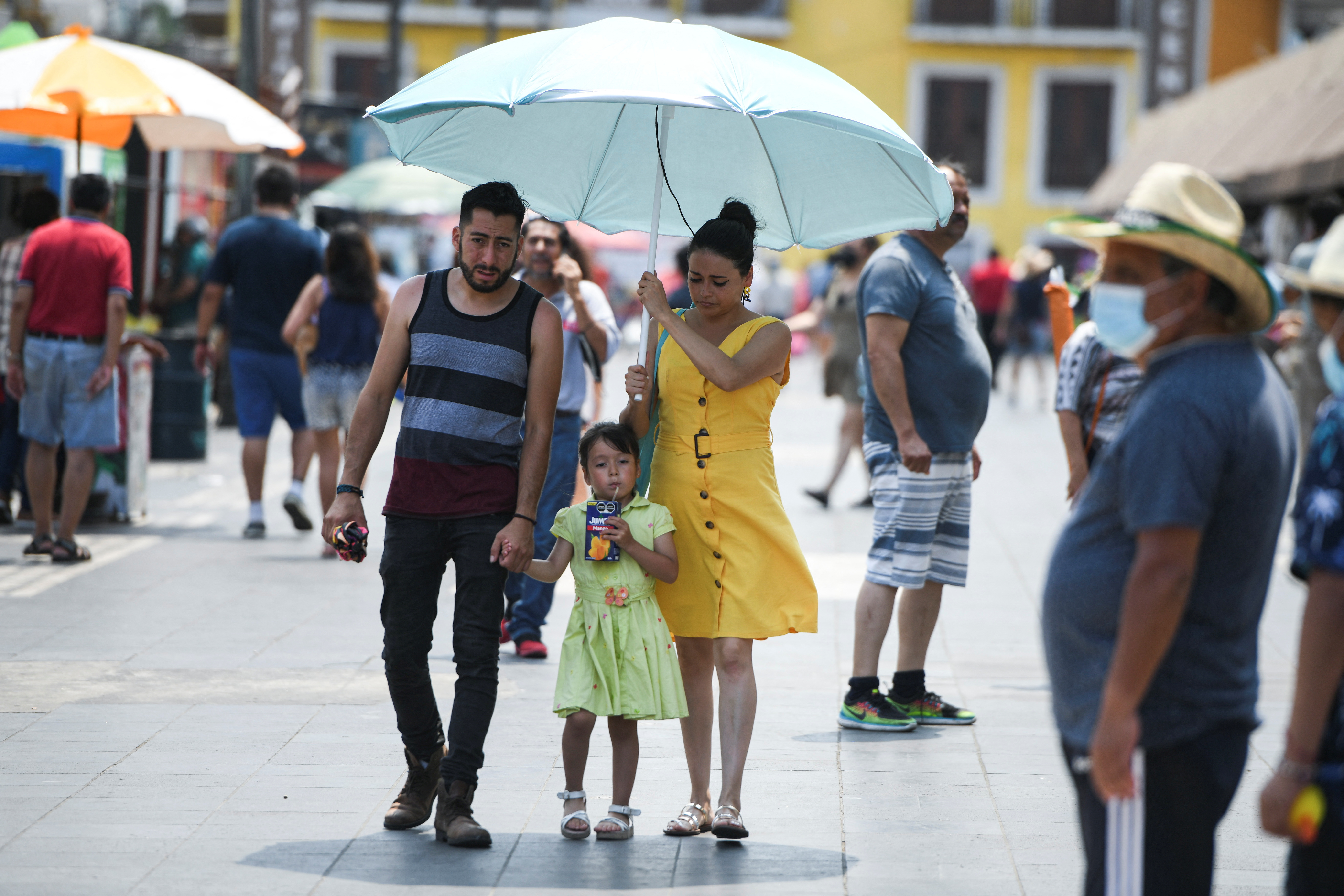 A family walks under an umbrella during a period of high temperatures in Veracruz, Mexico April 21, 2022. REUTERS/Yahir Ceballos
