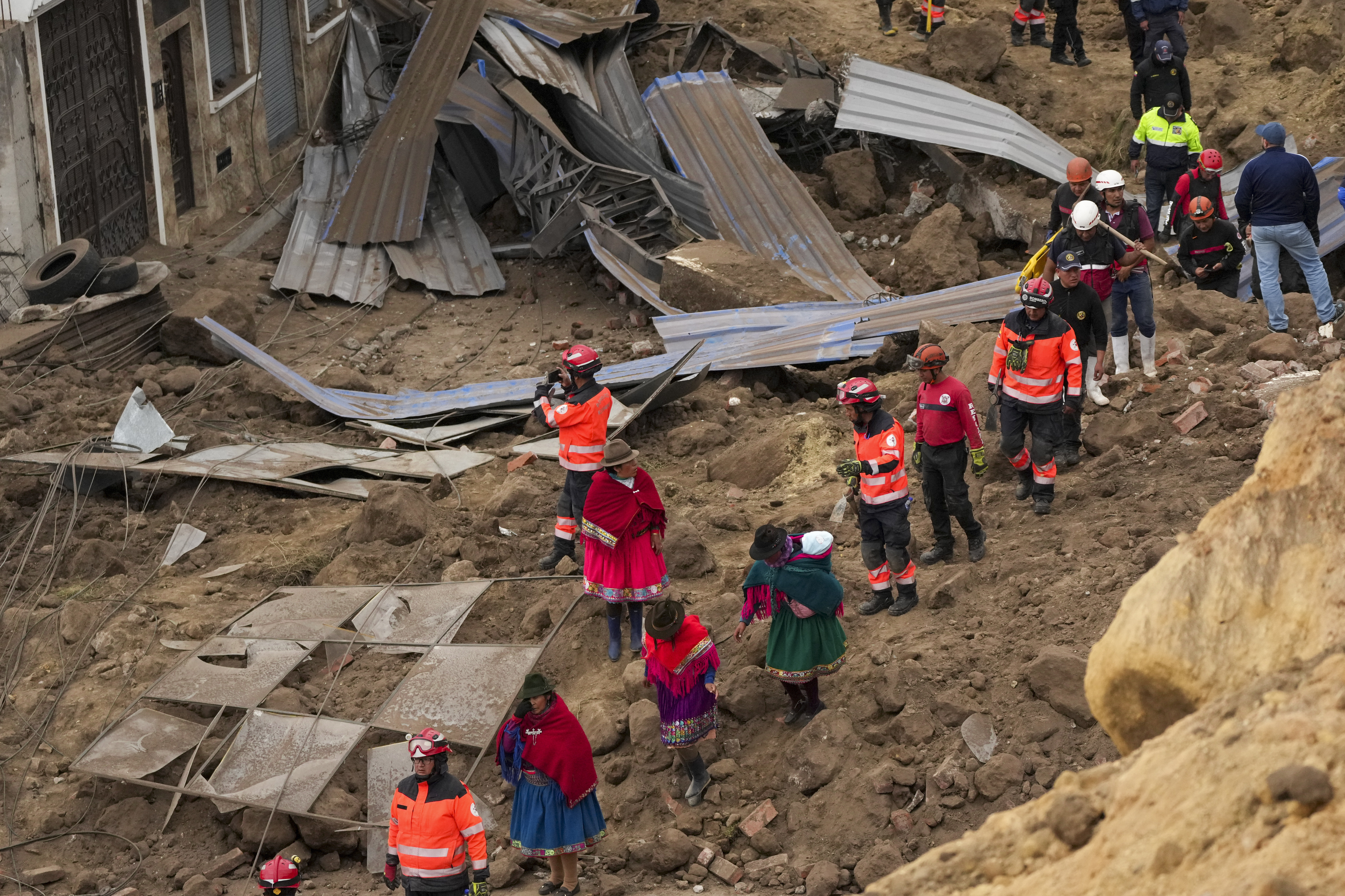 Rescatistas y residentes caminan entre escombros tras el mortífero alud, causado por las intensas lluvias, que enterró decenas de viviendas en Alausí, Ecuador, el lunes 27 de marzo de de 2023. (AP Foto/Dolores Ochoa)
