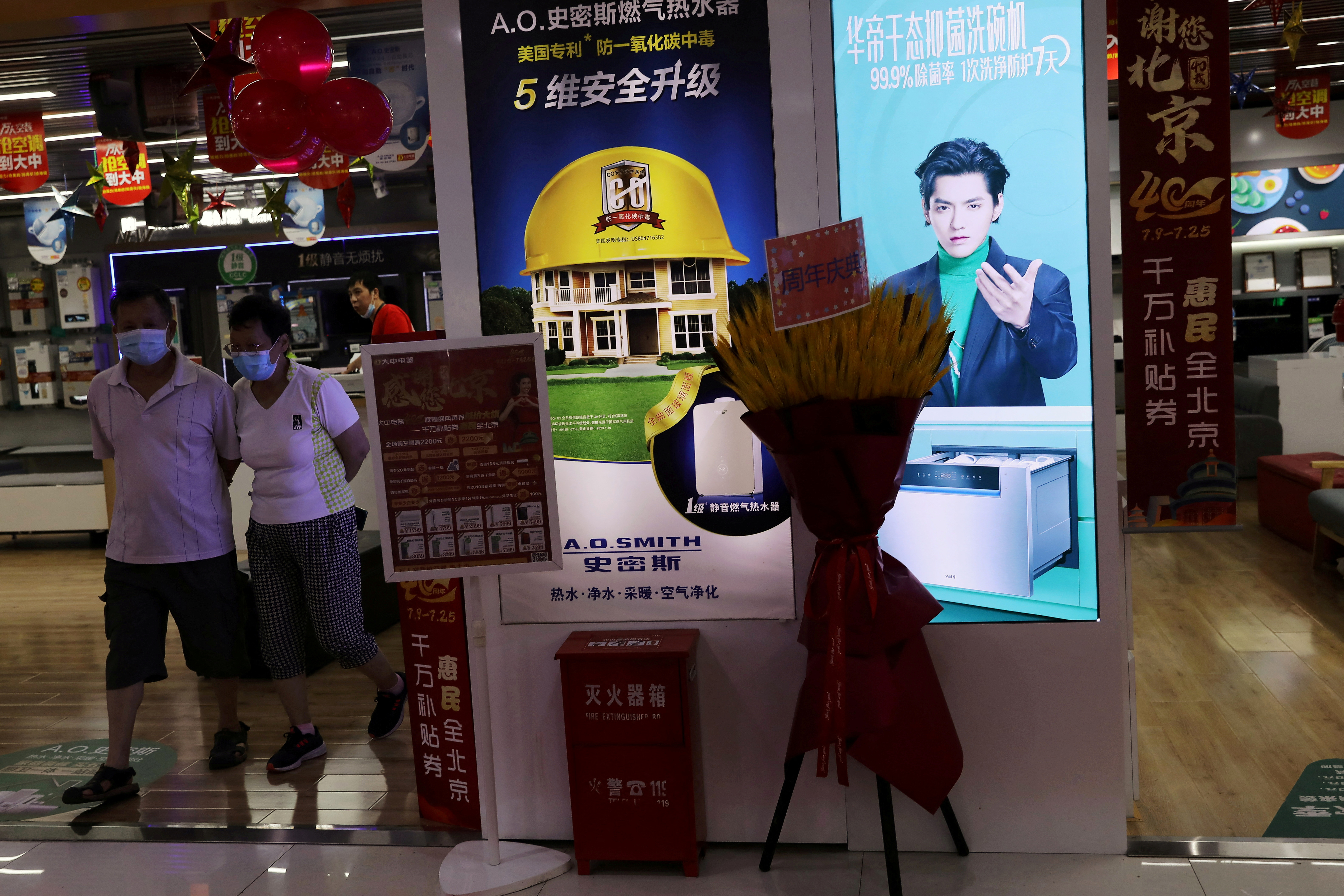 FOTO DE ARCHIVO: La gente camina junto a una tienda de electrodomésticos que muestra un anuncio que muestra al cantante y actor Kris Wu, en un centro comercial en Beijing, China, el 20 de julio de 2021. REUTERS/Tingshu Wang/Foto de archivo