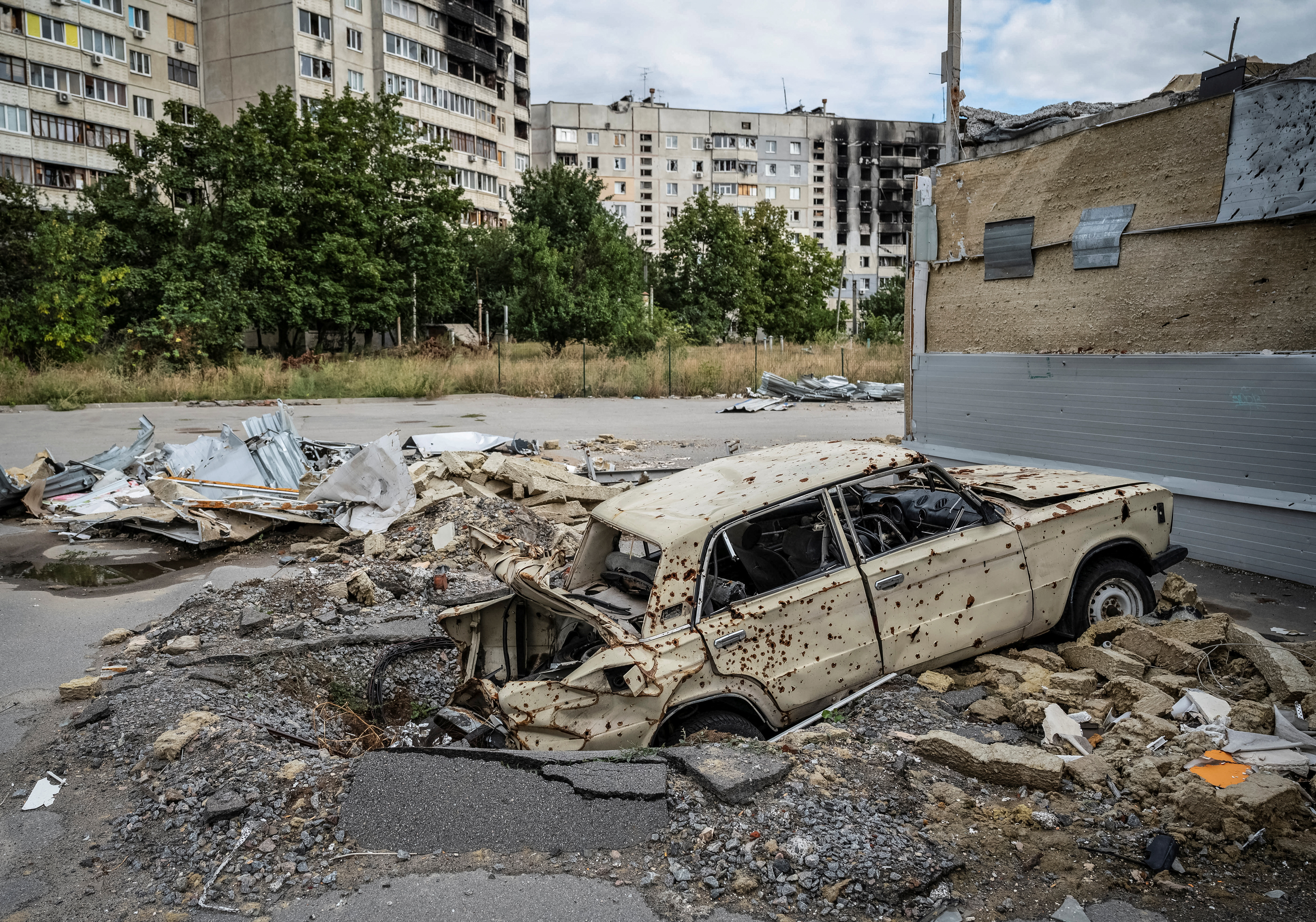 Un coche destruido es fotografiado delante de un edificio residencial dañado, en Saltivka, una de las zonas residenciales más dañadas, en medio del ataque de Rusia a Ucrania, en Kharkiv, Ucrania este 6 de septiembre de 2022 (Reuters)