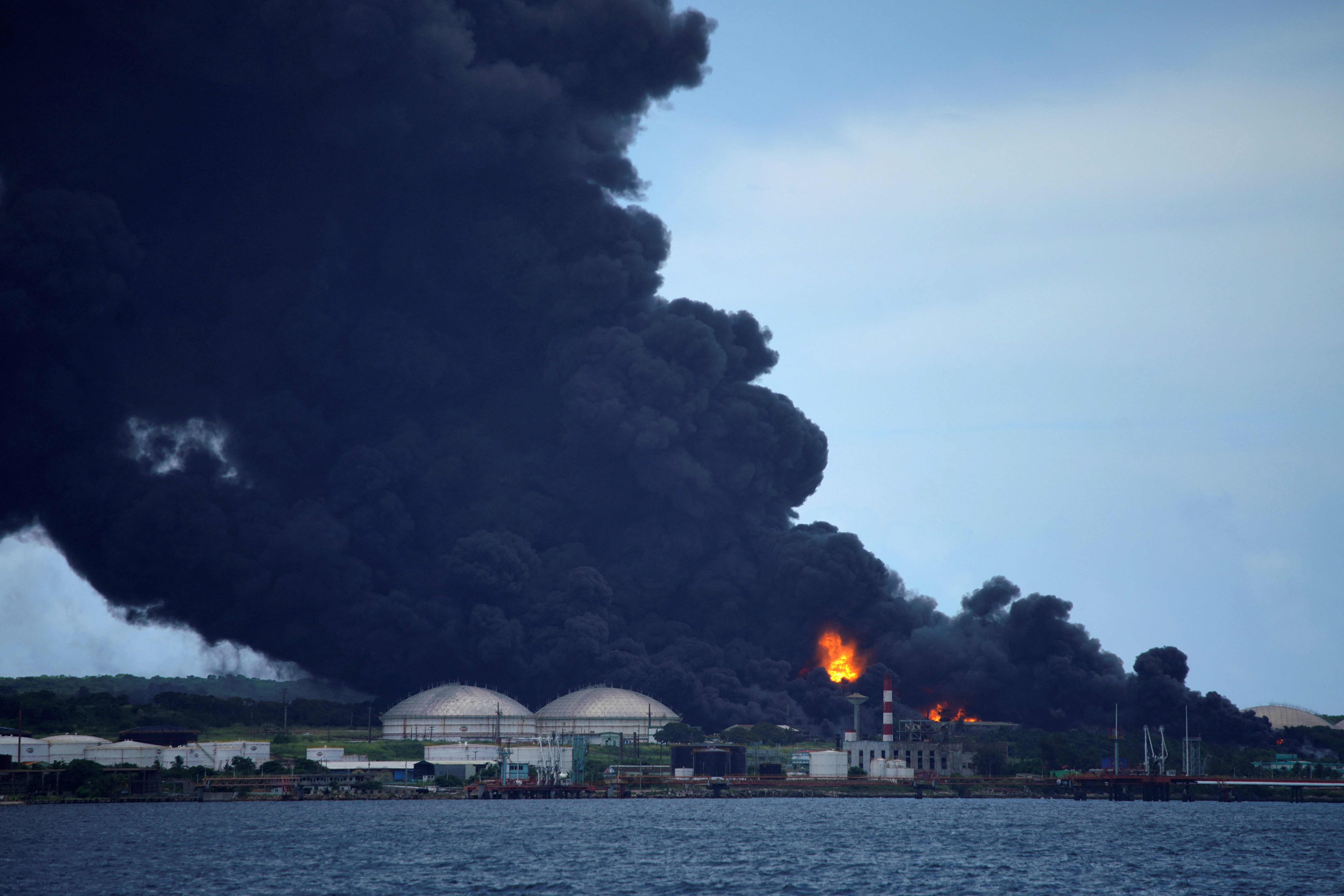 Fire is seen over fuel storage tanks that exploded near Cuba's supertanker port in Matanzas, Cuba, August 6, 2022. REUTERS/Alexandre Meneghini