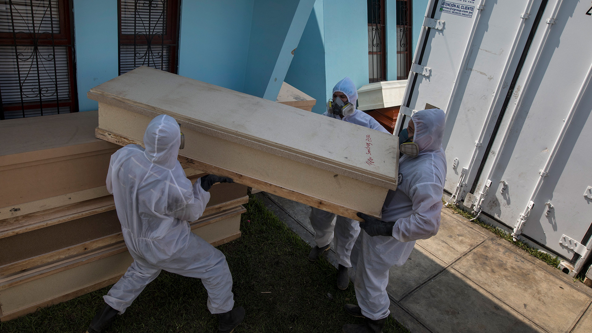 Trabajadores de una funeraria descargan un ataúd que contiene los restos de un difunto sospechoso de haber muerto por el nuevo coronavirus, fuera de un crematorio en Lima, Perú, el miércoles 20 de mayo de 2020 (AP Foto/Rodrigo Abd)