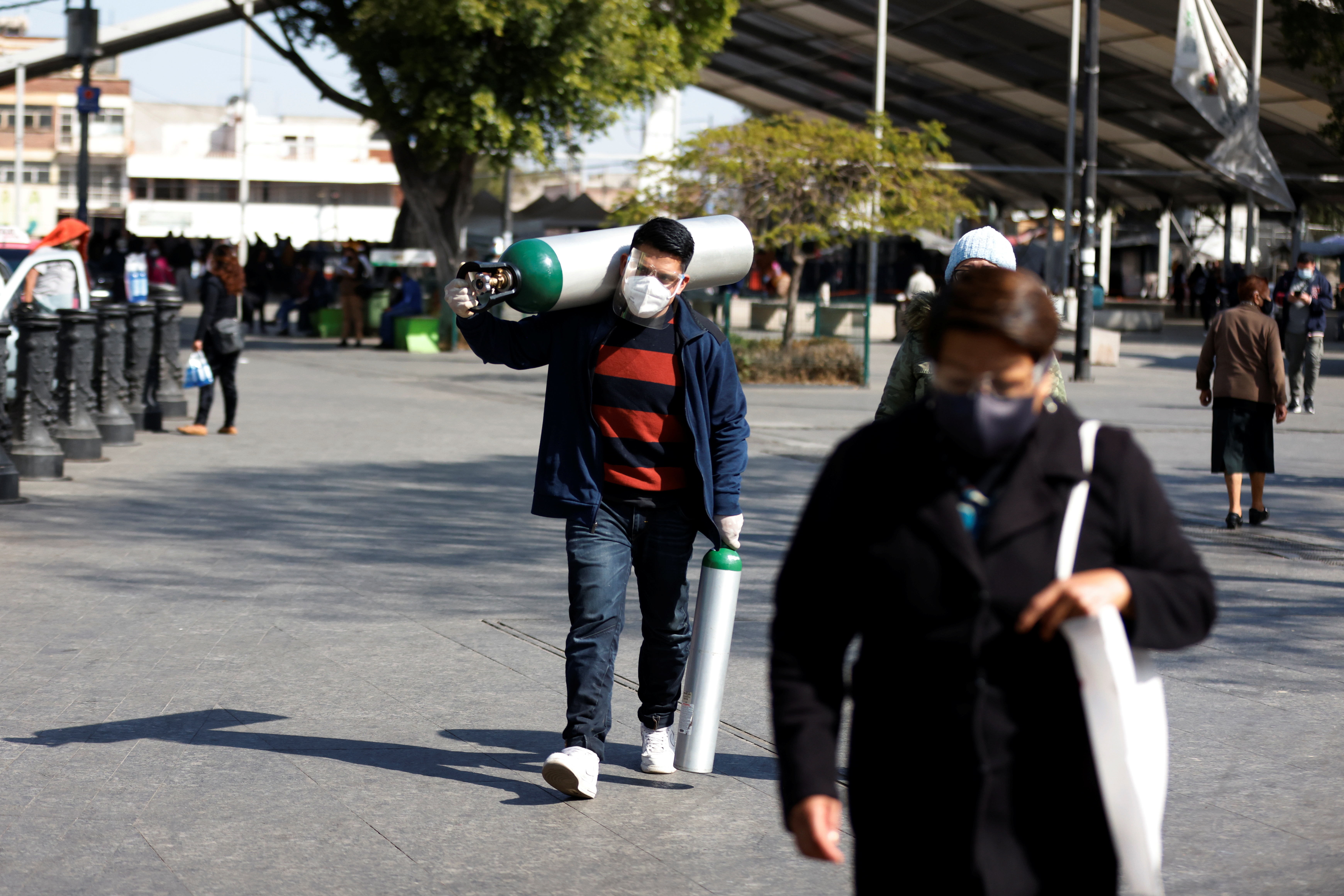 Un hombre lleva dos tanques de oxígeno después de llenarlos para un familiar infectado con la enfermedad del coronavirus, cerca de un puesto de oxígeno recargable gratuito provisto por el gobierno en la Ciudad de México, México, el 6 de enero de 2021.