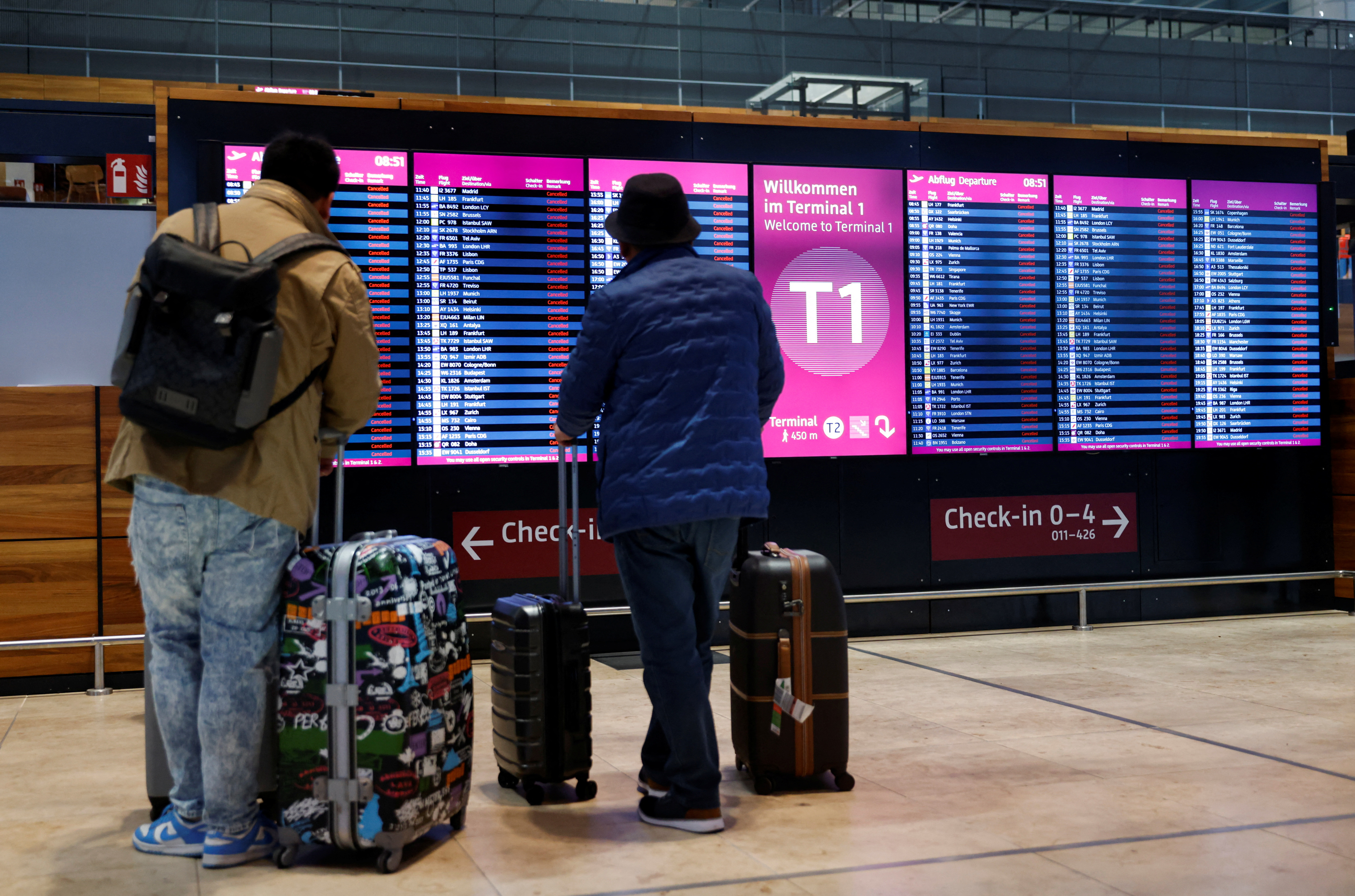 Passengers look at departure panels showing canceled flights during a general strike by employees over pay demands, at the Berlin Brandenburg Airport (BER), in Schoenefeld near Berlin, Germany January 25, 2023. REUTERS/Michele Tantussi