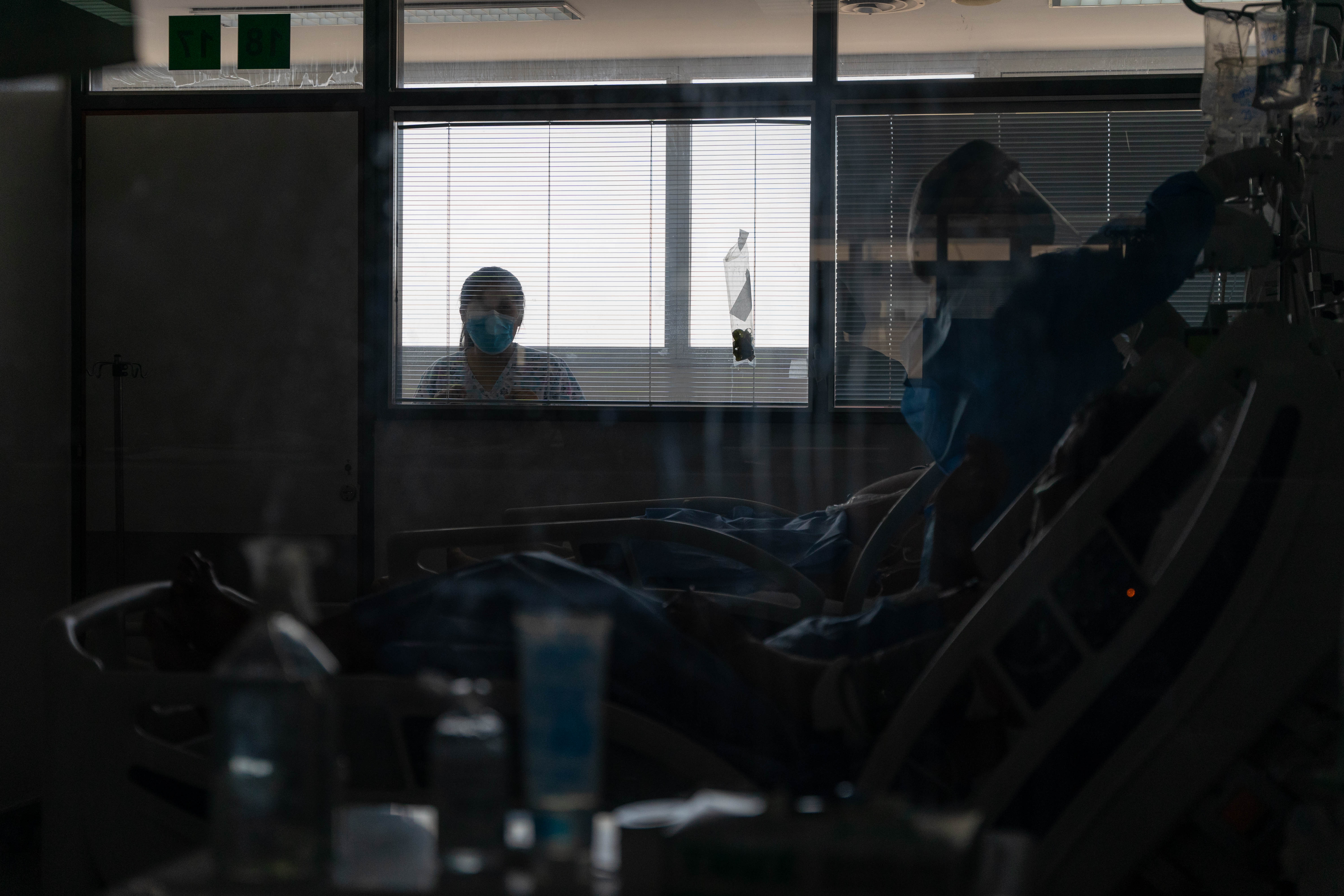 Una enfermera del hospital mira a su padre, internado en la UTI Covid.