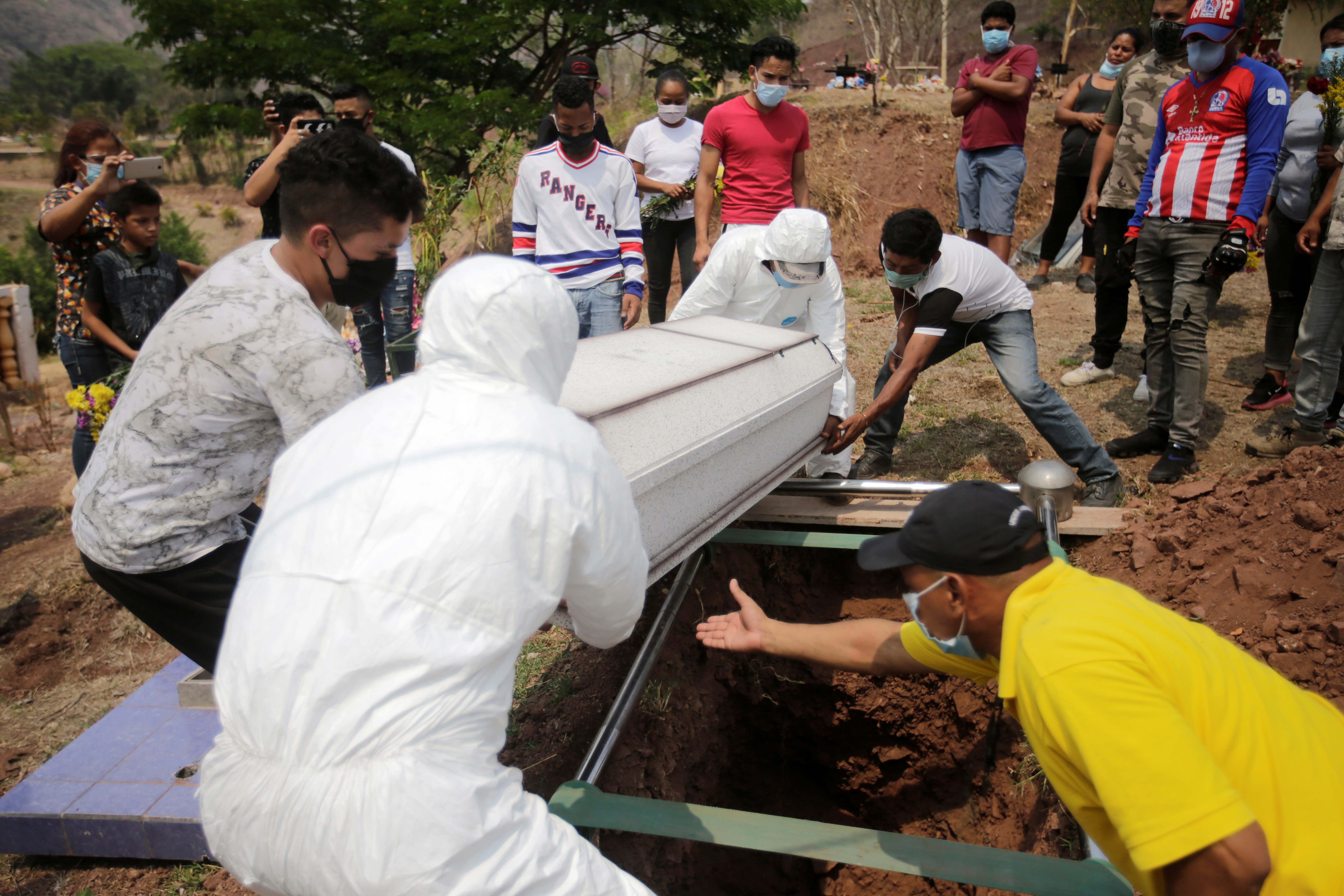 Trabajadores de una funeraria bajan un ataúd a la tumba en medio del brote de coronavirus en Tegucigalpa, Honduras, el 6 de mayo de 2020. (REUTERS/Jorge Cabrera)