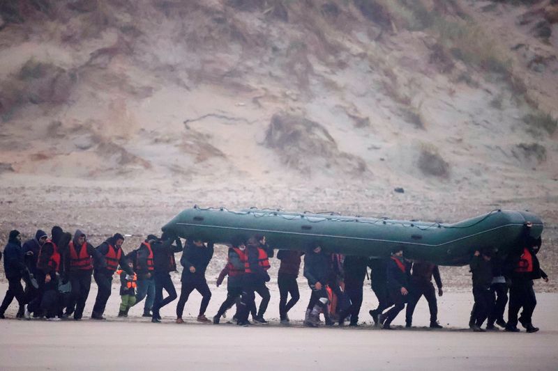Un grupo de más de 40 migrantes corre en la playa con un bote inflable, para dejar la costa del norte de Francia y cruzar el Canal de la Mancha, cerca de Wimereux, Francia. 24 de noviembre de 2021. REUTERS/Gonzalo Fuentes