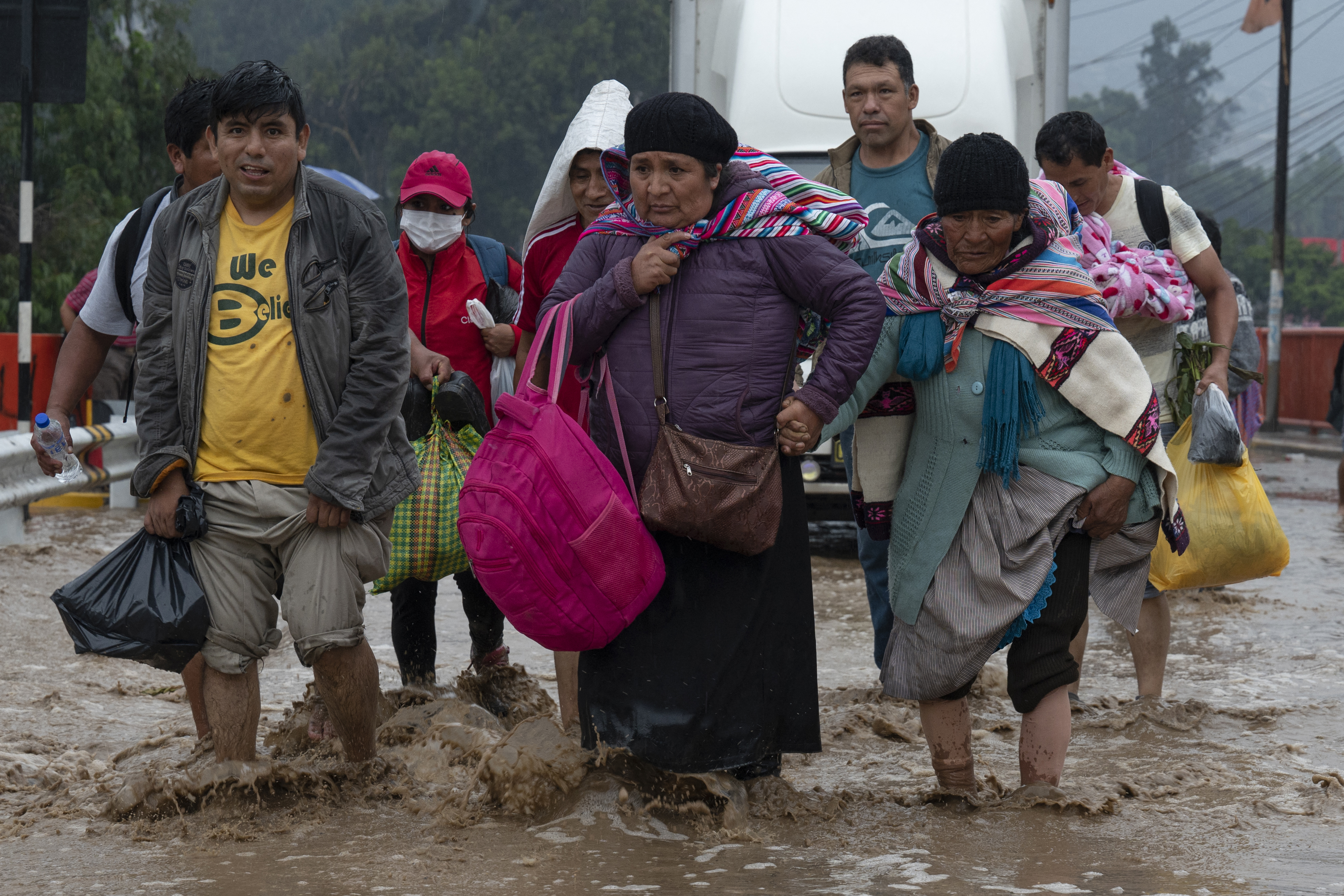 Las personas caminan a través del agua que inunda la principal vía de acceso desde Lima al interior del país en los Andes, luego de las fuertes lluvias en Chaclacayo. (AFP)