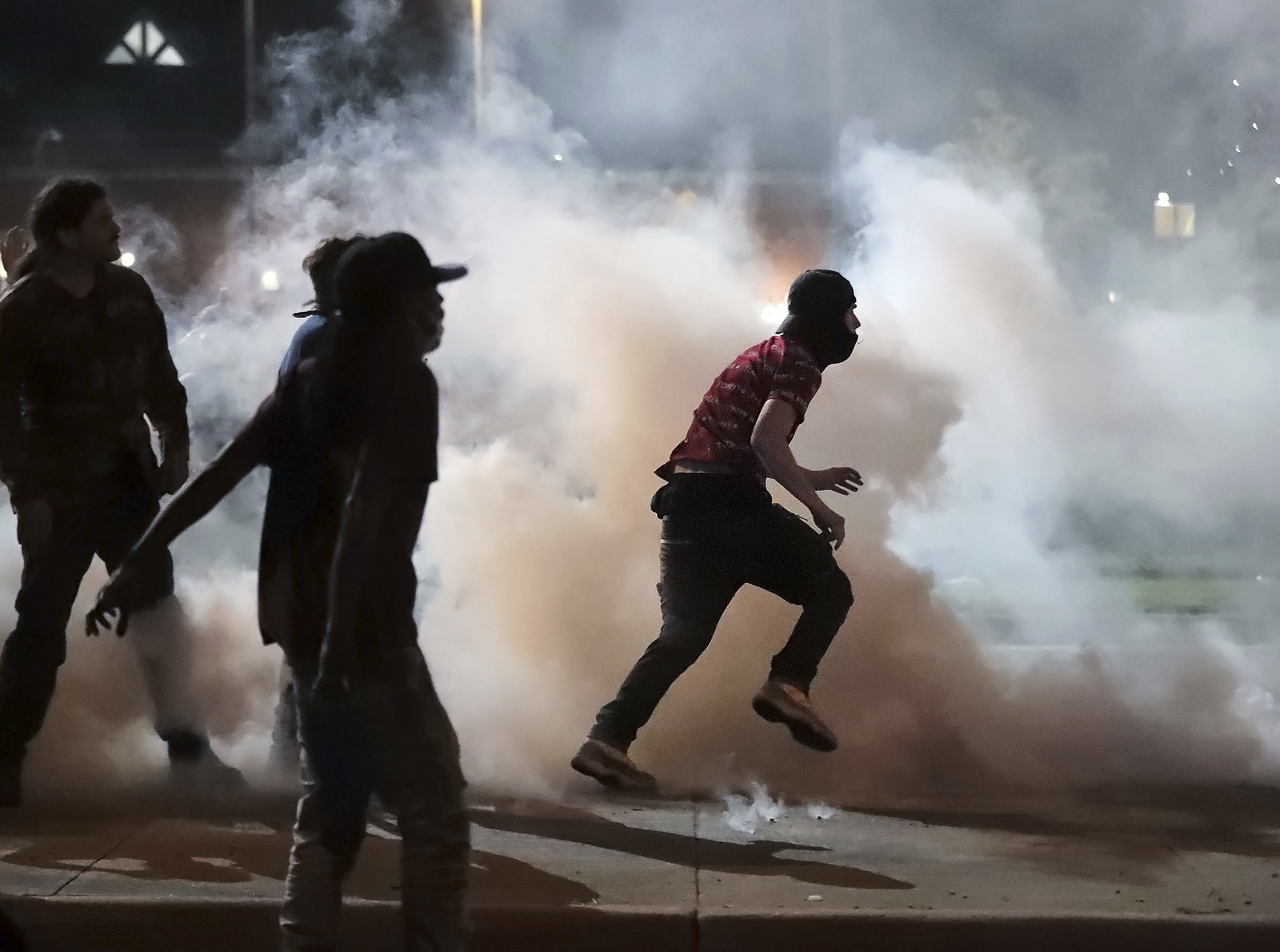 Las protestas, que suelen comenzar con un ambiente pacífico, derivan luego en incidentes con las fuerzas de seguridad, pese a la declaración del toque de queda en al menos cuarenta ciudades del país y la activación de la Guardia Nacional en quince estados y en la ciudad de Washington, la capital. En la foto, manifestantes arrojan bombas de humo a los agentes del alguacil del Condado de Shelby, en Tennessee, este domingo (Jim Weber/Daily Memphian via AP)