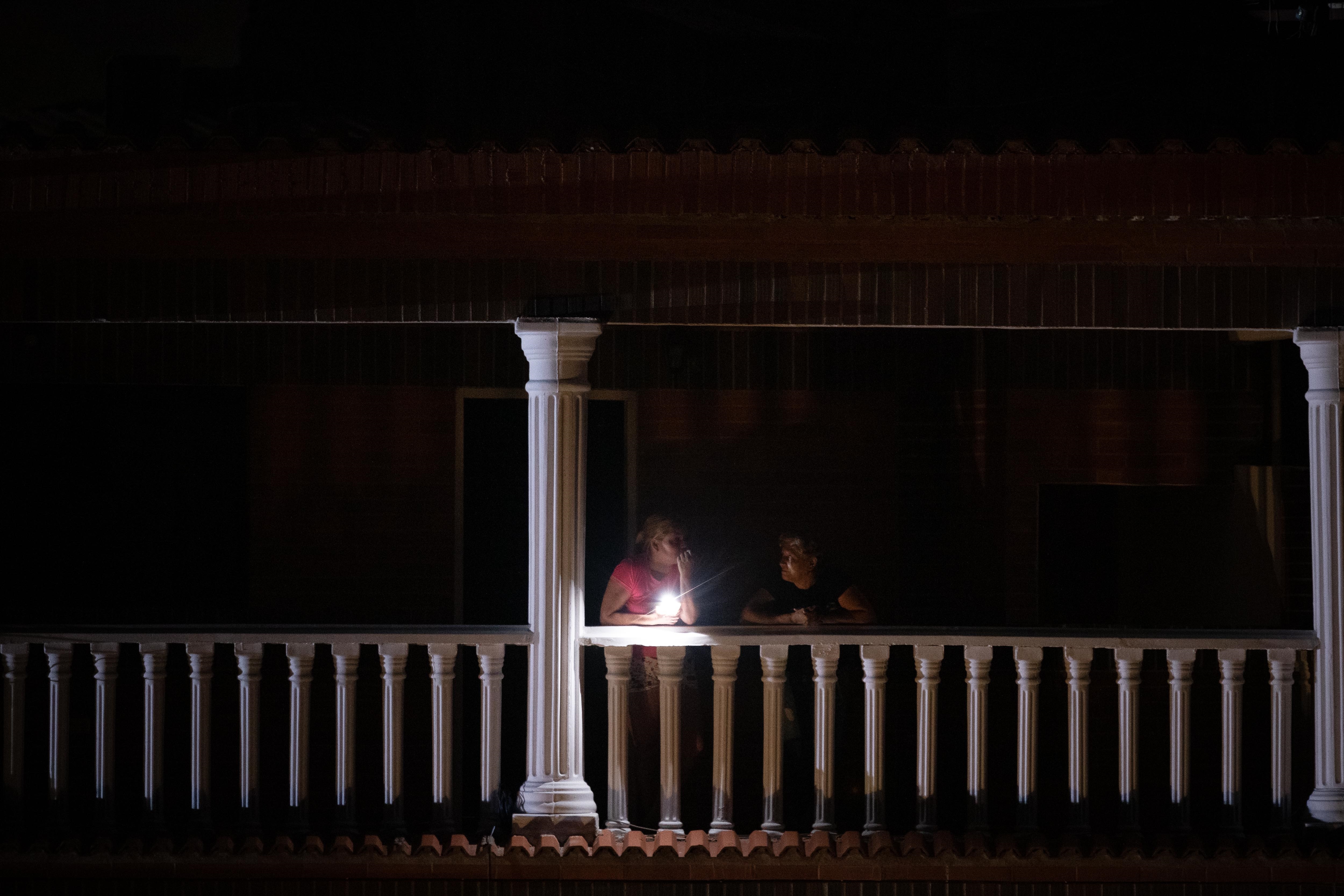 Dos mujeres esperan en un balcón, durante un apagón en Caracas 

