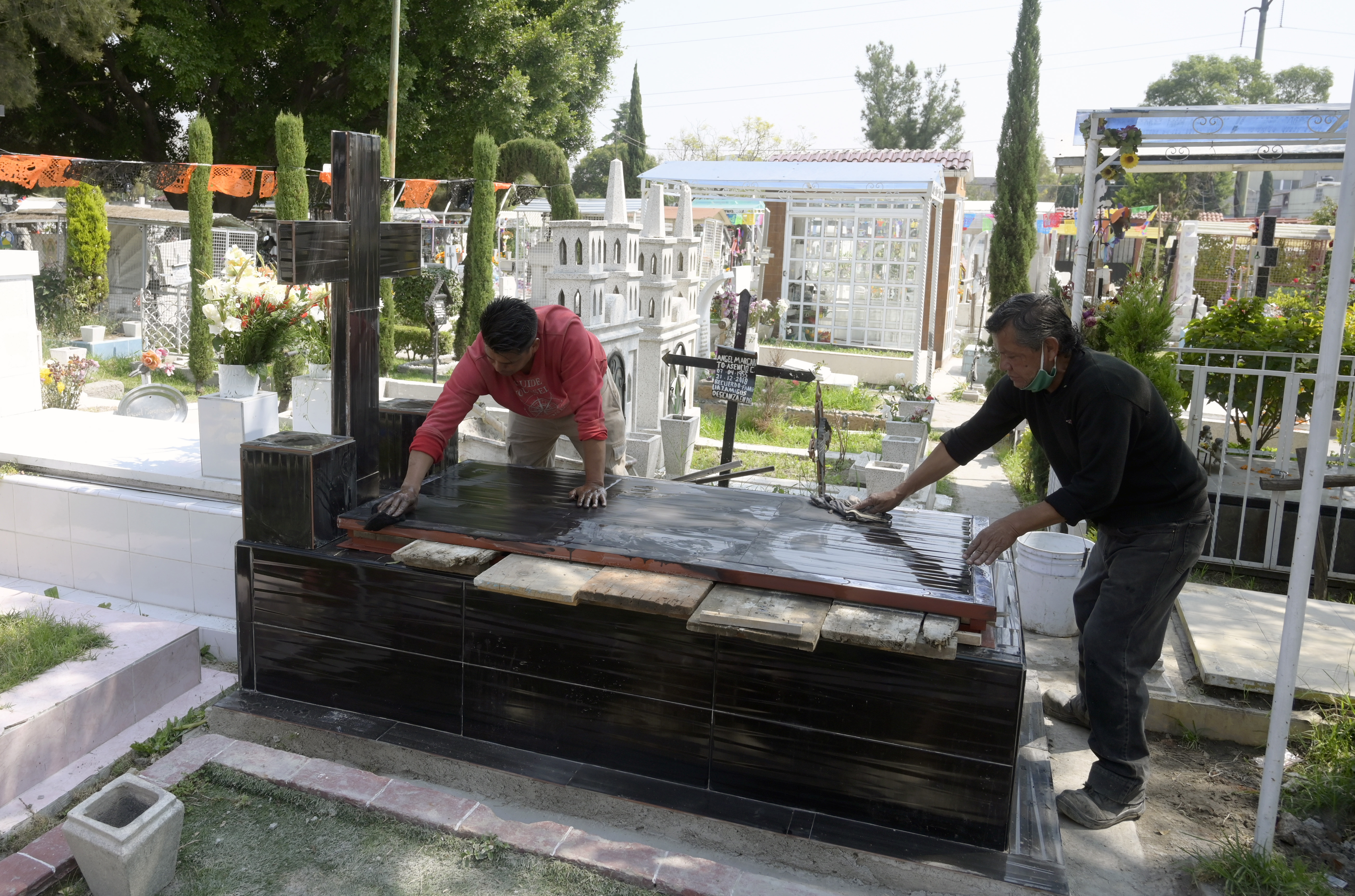 Dos empleados preparan una tumba antes del Día de Muertos en el Panteón San José, en la Ciudad de México el 28 de octubre de 2020.