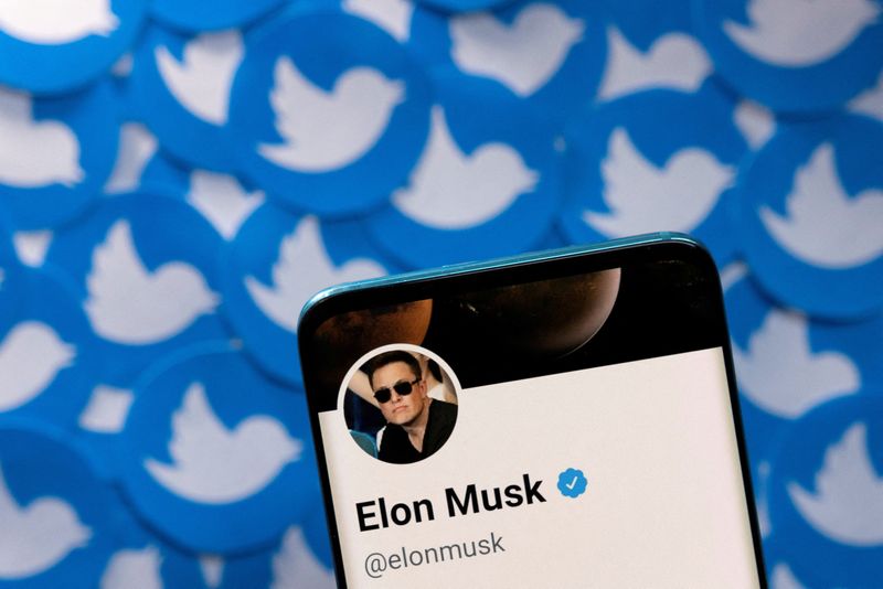 Imagen del perfil de Twitter de Elon Musk en la pantalla de un teléfono móvil sobre varias reproducciones impresas del logotipo de la red social en esta imagen de ilustración tomada el 28 de abril de 2022. REUTERS/Dado Ruvic