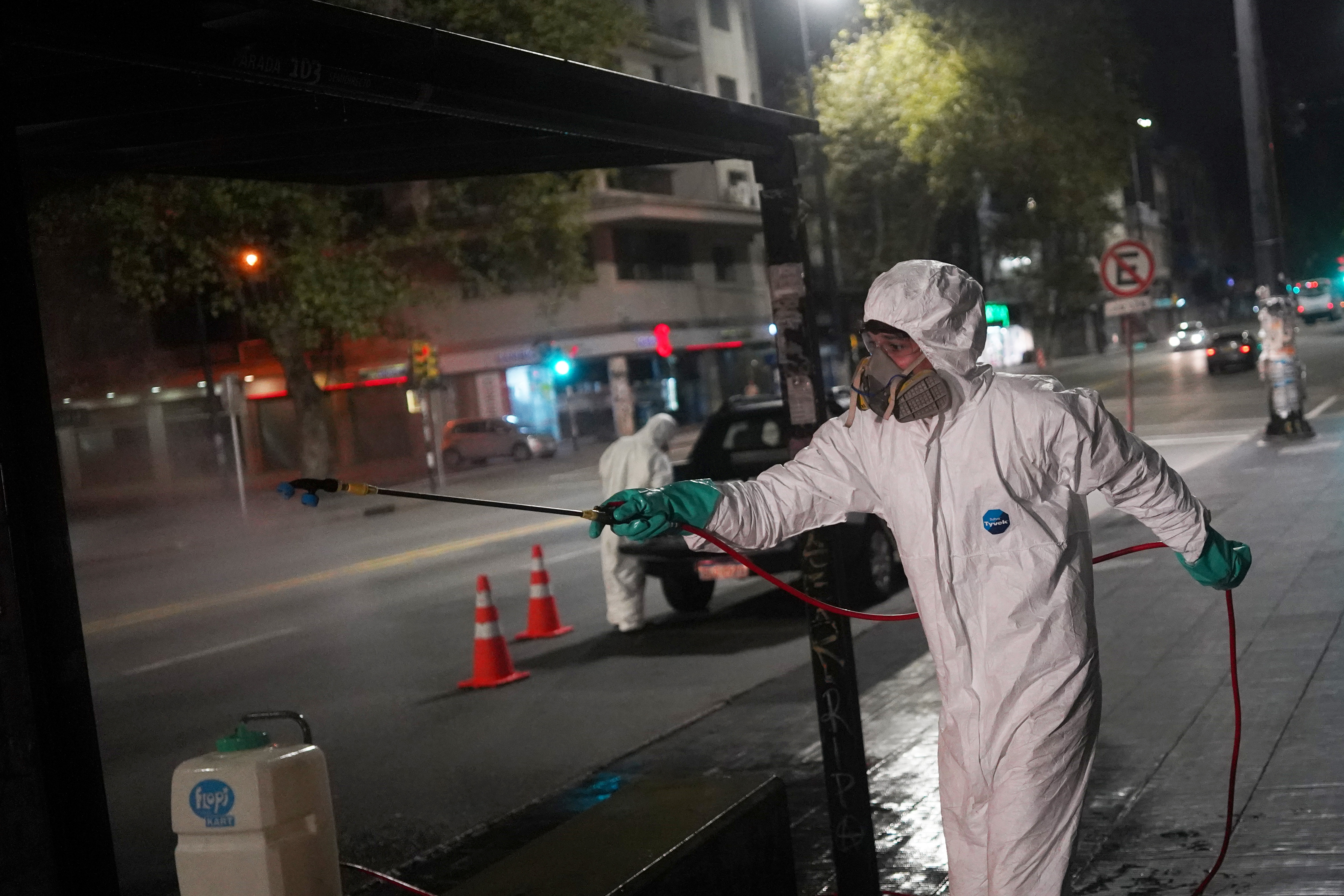 Trabajadores municipales desinfectan un área alrededor de una parada de autobús en Montevideo, el 19 de abril de 2020.  (REUTERS/Mariana Greif)