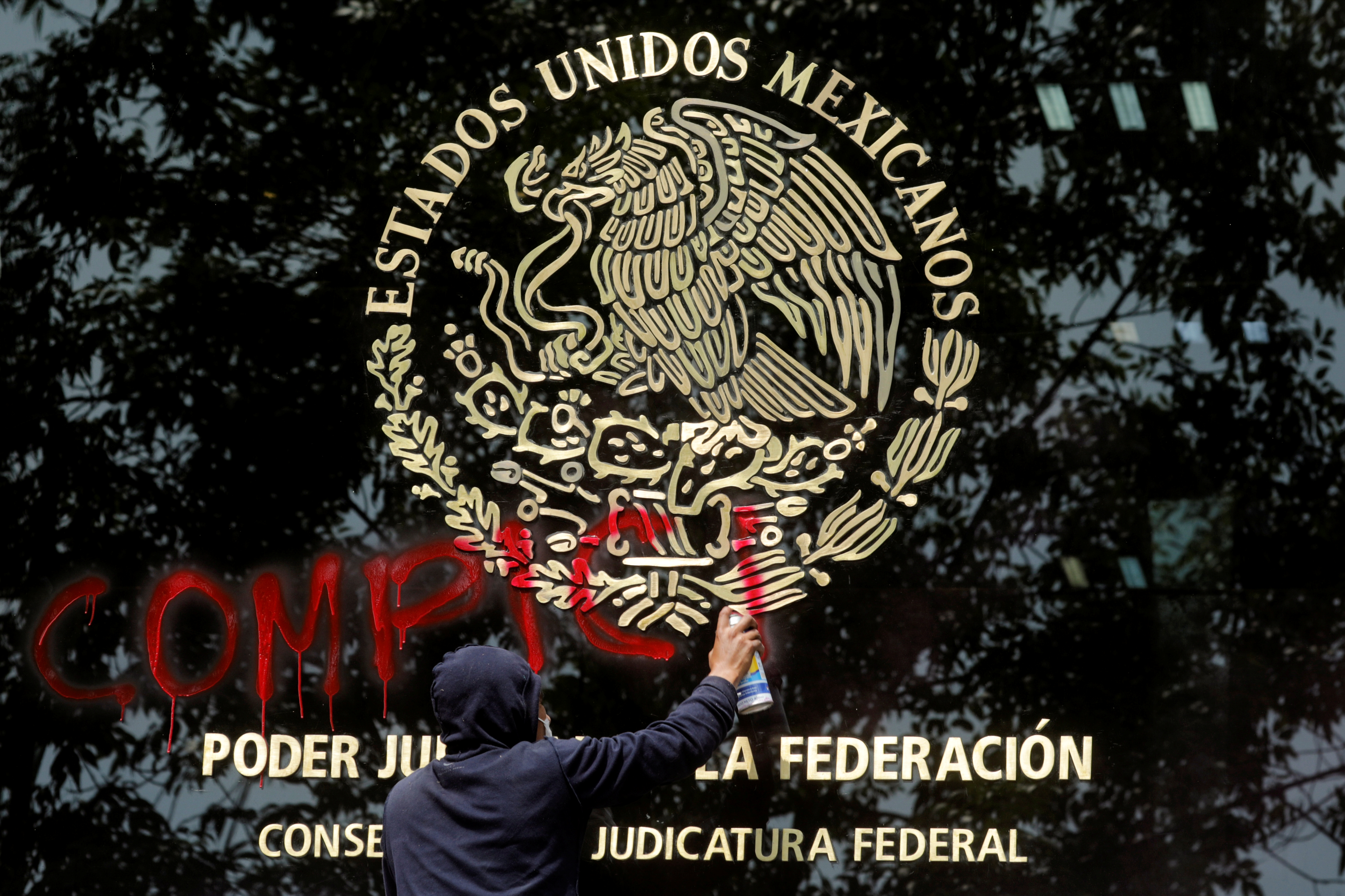 Un manifestante pinta graffiti en la fachada del Consejo de la Judicatura Federal, durante una protesta antes del sexto aniversario de la desaparición de 43 estudiantes de la Escuela Normal Rural de Ayotzinapa, en la Ciudad de México, México 24 de septiembre de 2020.