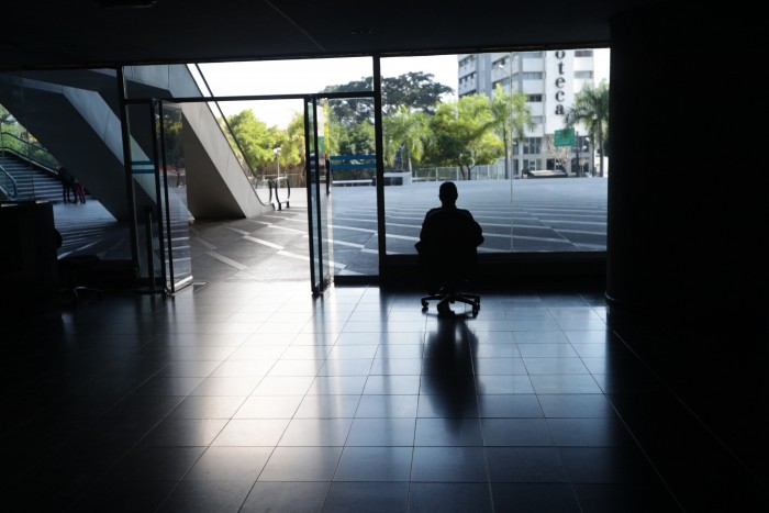 Un hombre mira por la ventana en una oficina sin luz en Caracas (EFE/Rayner Peña/Archivo)