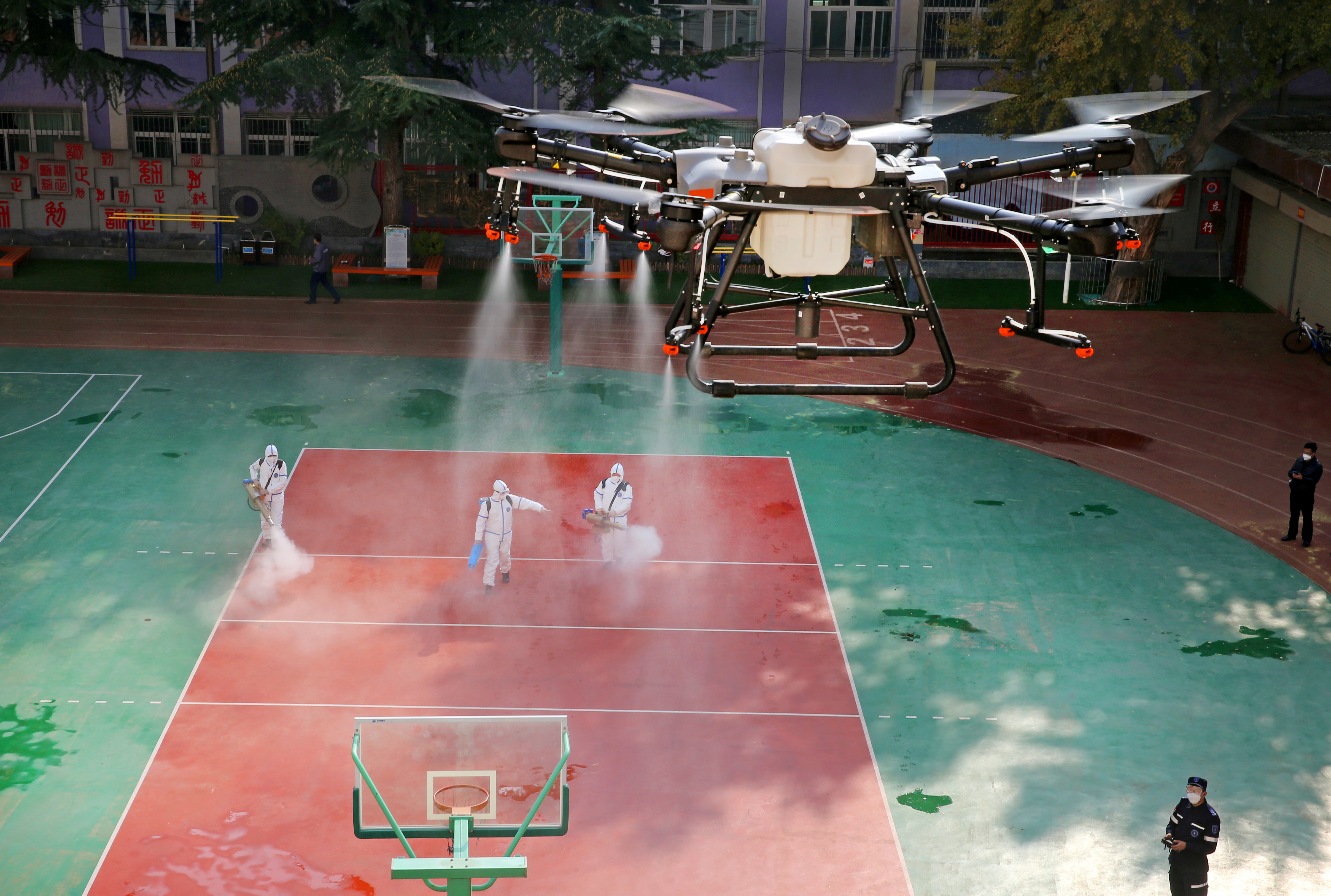 Un dron rocía desinfectante en escuela después de casos locales de covid en Lanzhou. La estrategia de "cero COVID" de China podría volverse cada vez más insostenible frente a la variante ómicron  (China Daily via REUTERS)