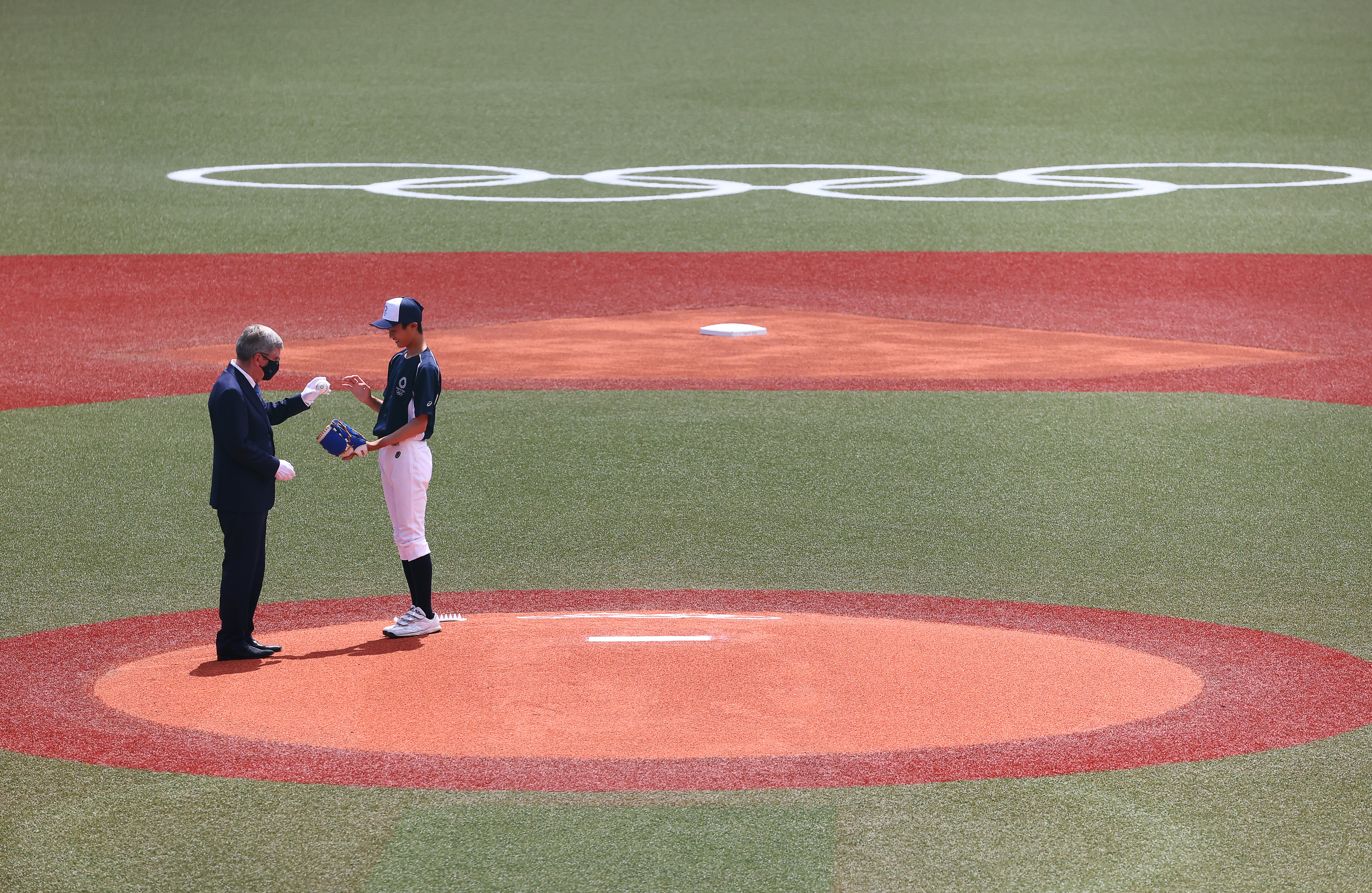 Tokyo 2020 Olympics - Baseball - Men - Opening Round - Group A - Dominican Republic v Japan - Fukushima Azuma Baseball Stadium, Fukushima, Japan – July 28, 2021. International Olympic Commission (IOC) President Thomas Bach hands a ball to a Japanese student to take the first pitch. REUTERS/Jorge Silva