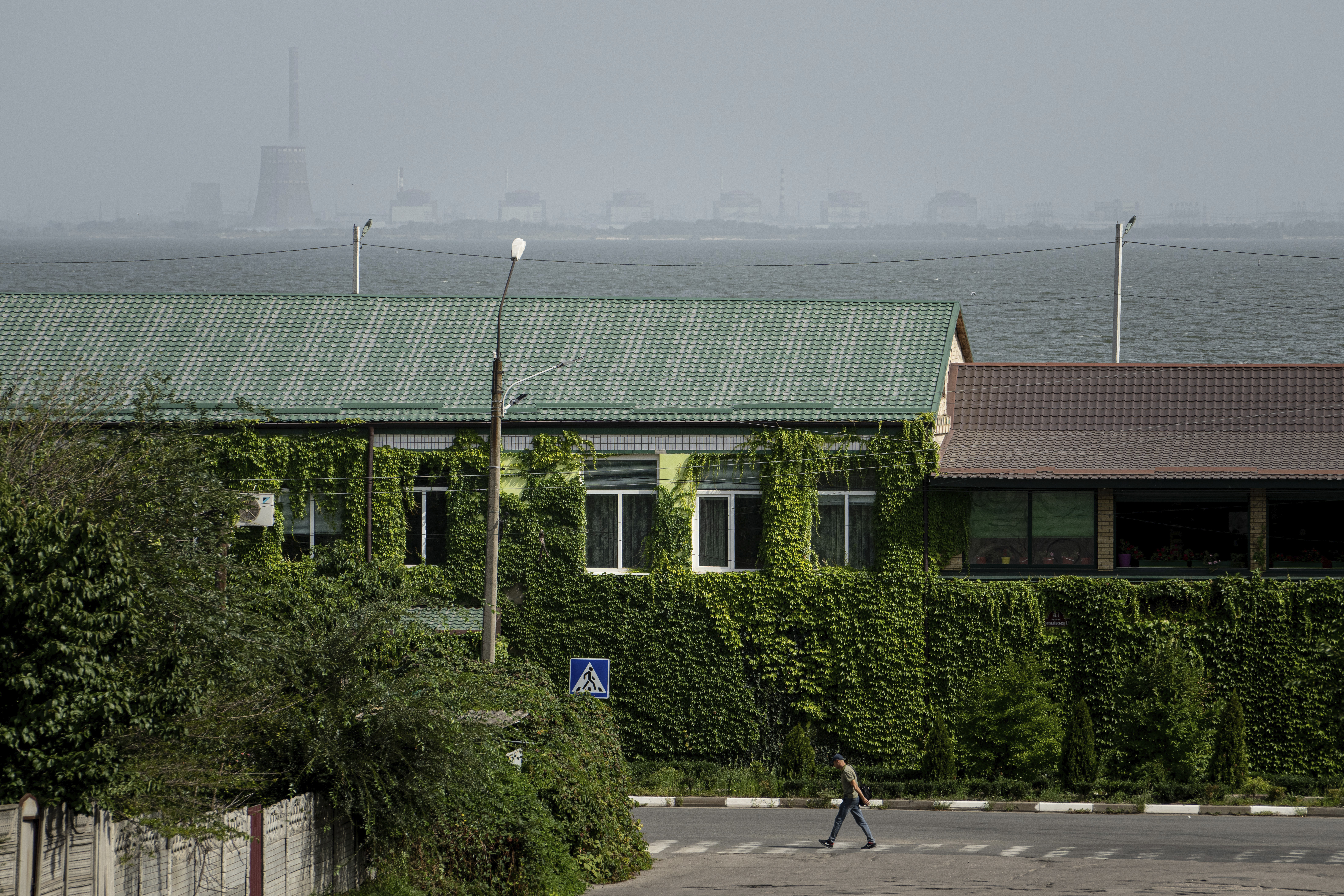 A man walks near the Dnipro River and the Zaporizhzhia nuclear power plant in Nikopol, Ukraine (AP Photo/Evgeniy Maloletka, File)