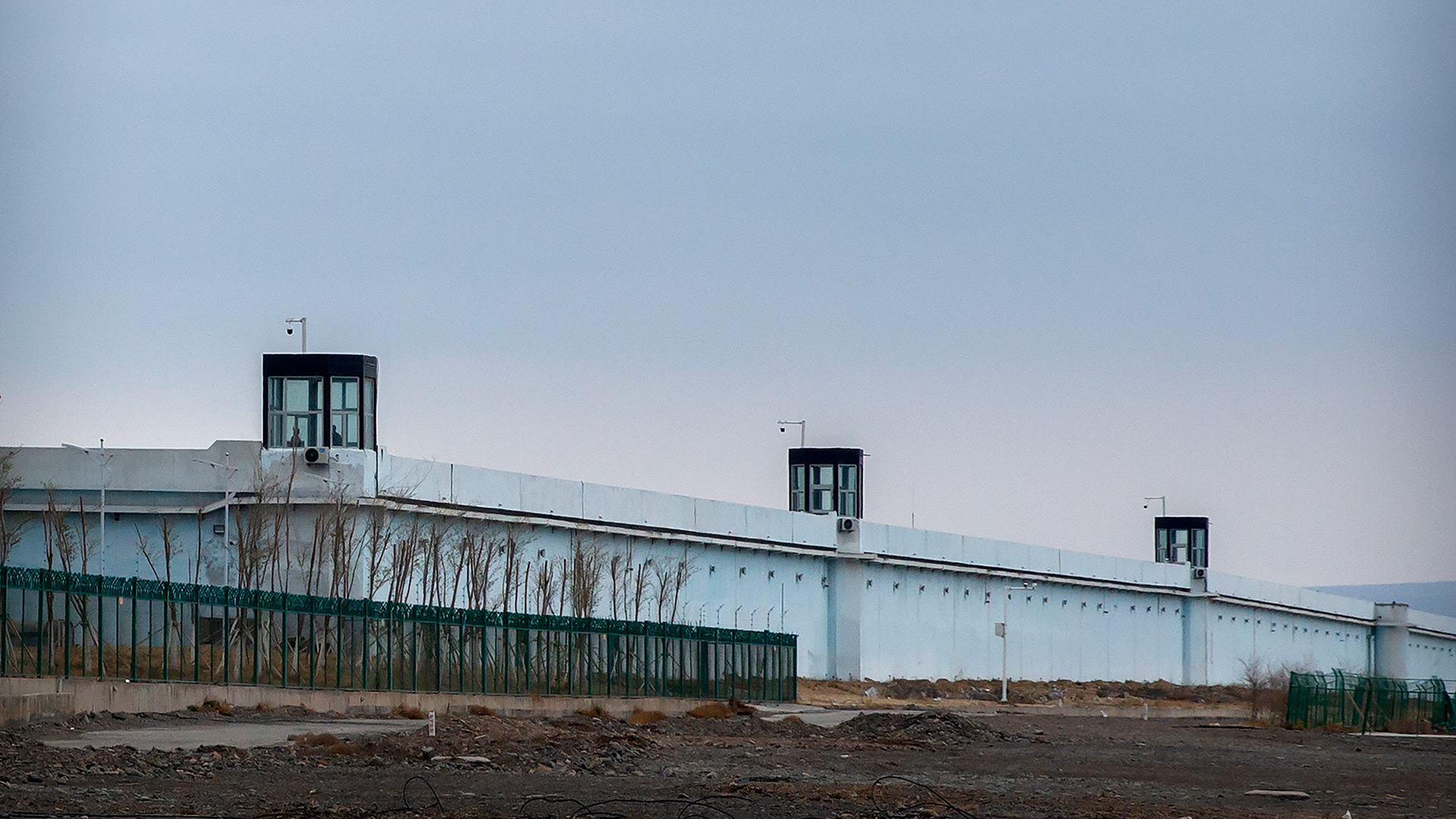 Unas personas permanecen en una torre de vigilancia en el muro perimetral del Centro de Detención nº 3 de Urumqi, en Dabancheng, en la región autónoma uigur de Xinjiang, en el oeste de China, el 23 de abril de 2021 (AP Photo/Mark Schiefelbein)