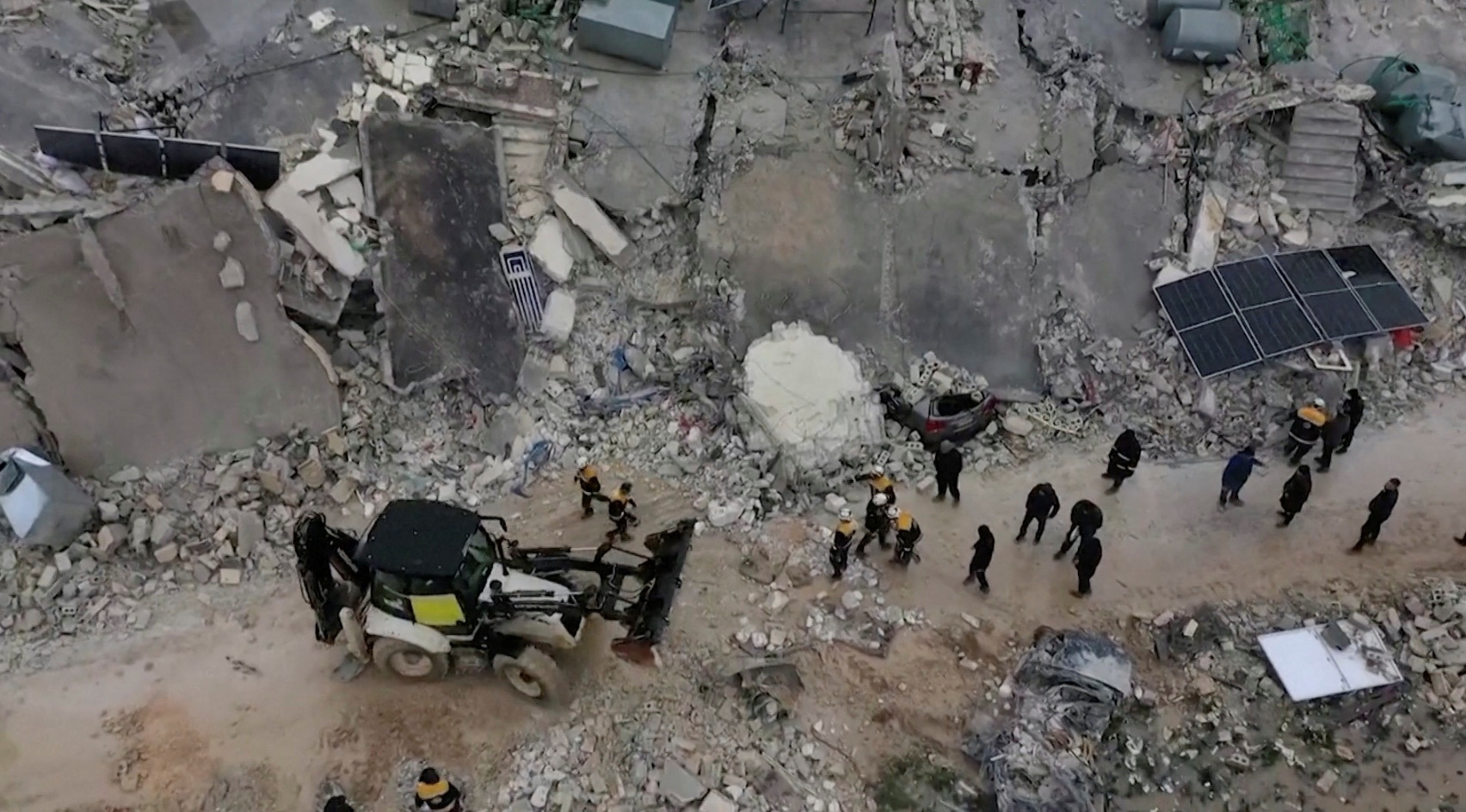 Los rescatistas se reúnen entre los escombros de los edificios derrumbados tras un terremoto, en la ciudad rebelde de Sarmada, Siria.
