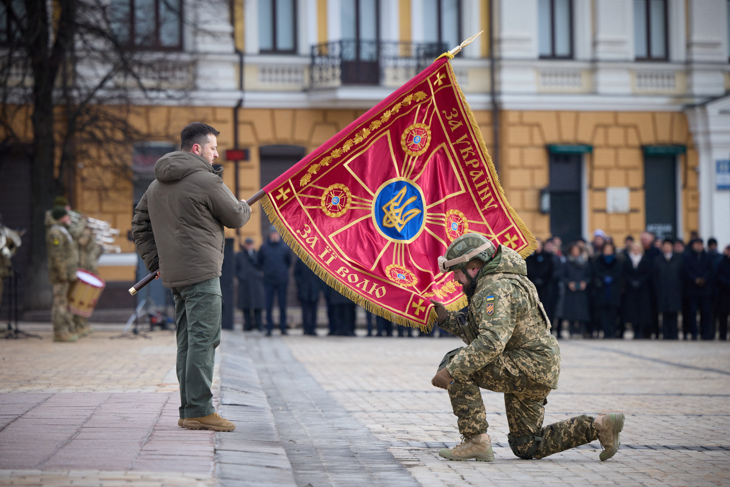 El presidente ucraniano Volodimir Zelensky ondea una bandera sobre un soldado durante una ceremonia por el primer aniversario de la invasión rusa a su país en Kiev (Presidential Press Service/Handout via REUTERS)