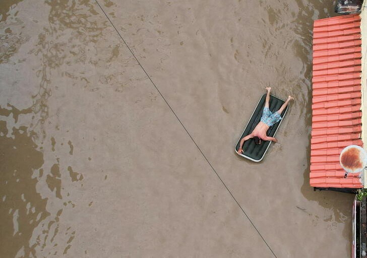 Un hombre utiliza un colchón inflable en medio de una inundación causada por el desborde del río Cachoeira en Itabuna, estado de Bahía, Brasil (REUTERS/Leonardo Benassatto)