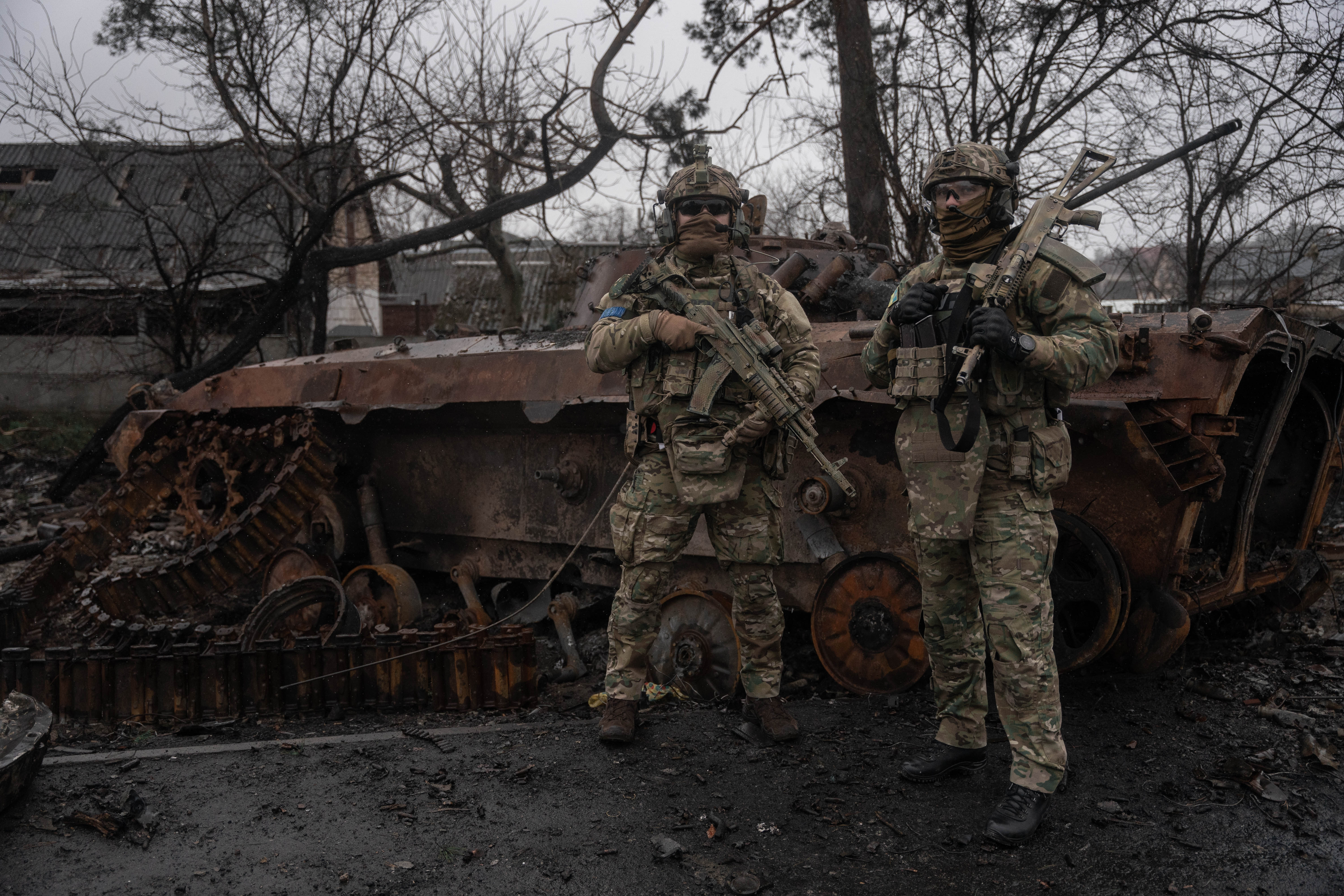 Militares ucranianos posan frente a un tanque ruso completamente destrozado a las afueras de Kyiv.