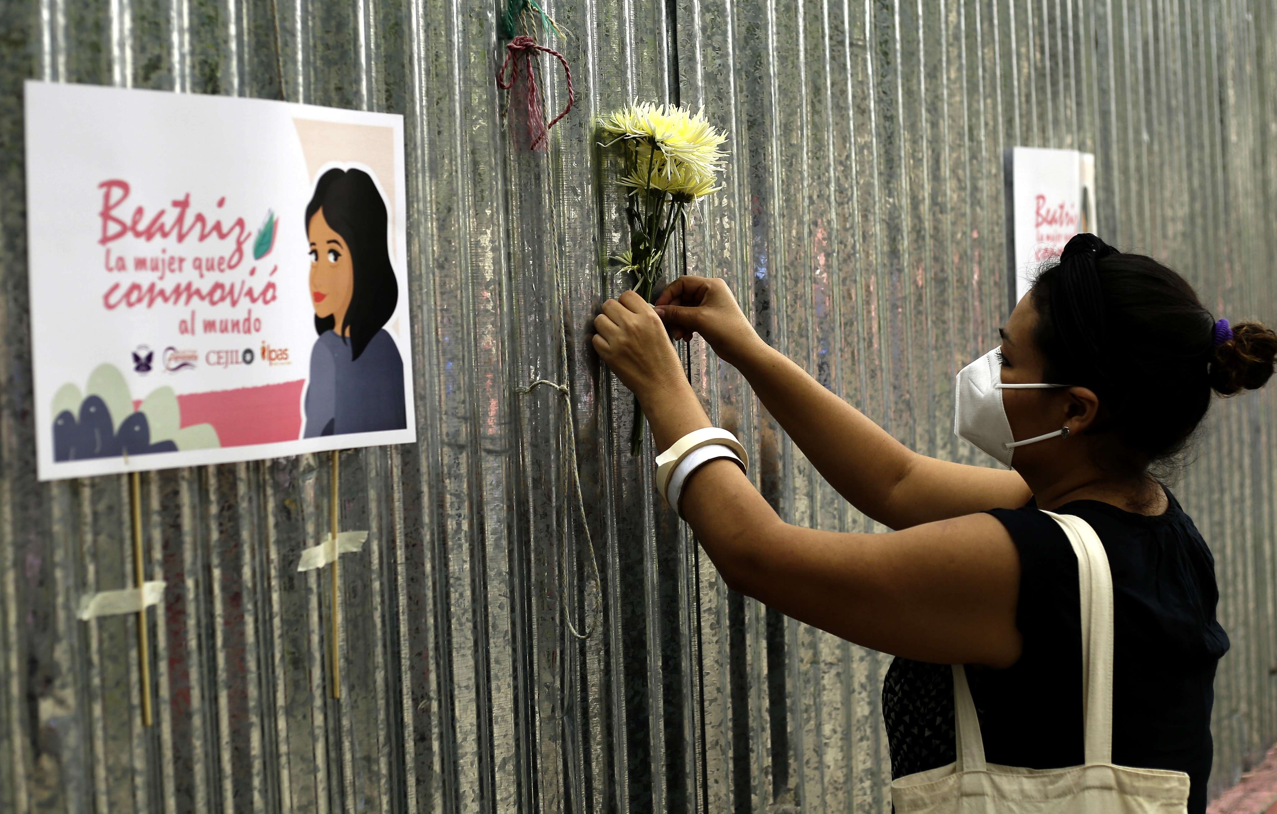 Una mujer coloca unas flores junto a un cartel conmemorativo en honor a &quot;Beatriz&quot;, el nombre ficticio con el que se conoci&#243; a una joven de 22 a&#241;os que padec&#237;a lupus y que pidi&#243; a la Corte Suprema de Justicia abortar en 2013, sin obtener un resultado positivo, durante un acto hoy, en San Salvador (El Salvador). EFE/ Rodrigo Sura
