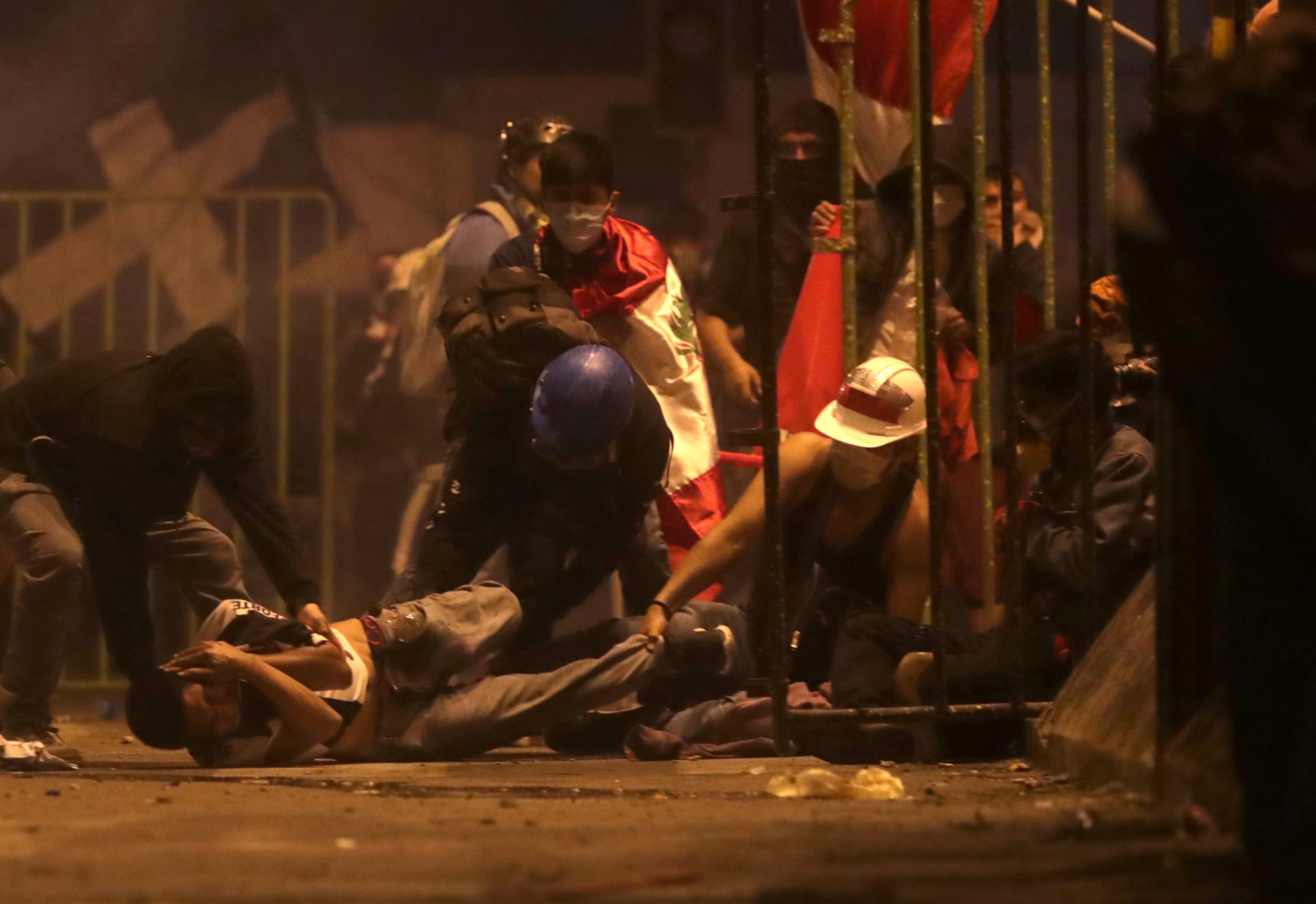 Un manifestante cae herido en el piso mientra otros tratan de ayudarlo durante de las protestas contra el nuevo presidente de Perú 