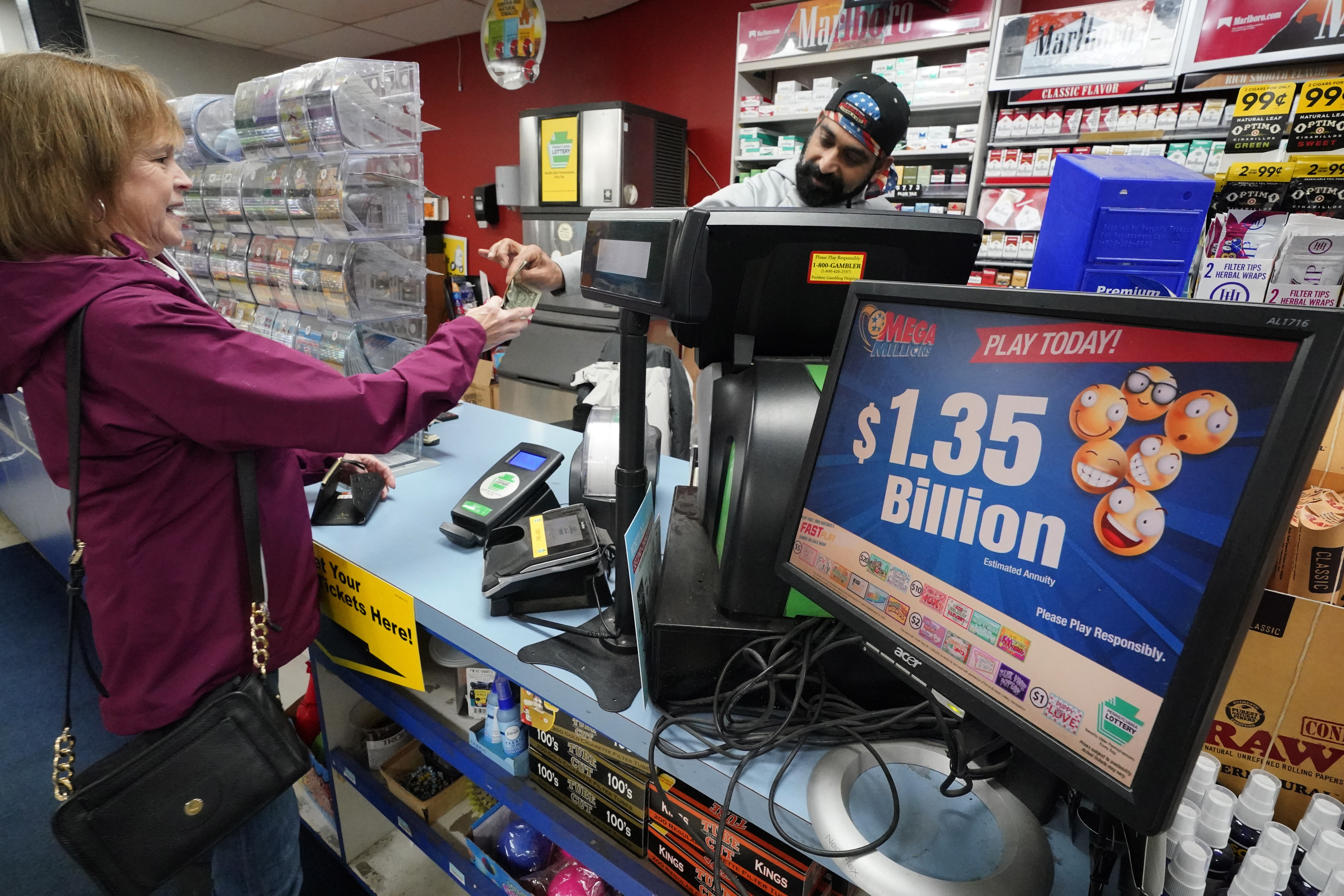 En esta imagen de archivo, un cartel anuncia el bote estimado de la lotería Mega Millions mientras una persona compra un boleto en el Cranberry Super Mini Mart en Cranberry, Pensilvania, el 12 de enero de 2023. ( AP Foto/Gene J. Puskar, archivo)