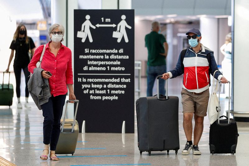 Pasajeros con mascarillas protectoras caminan en el aeropuerto de Fiumicino, en Roma, Italia. REUTERS/Guglielmo Mangiapane