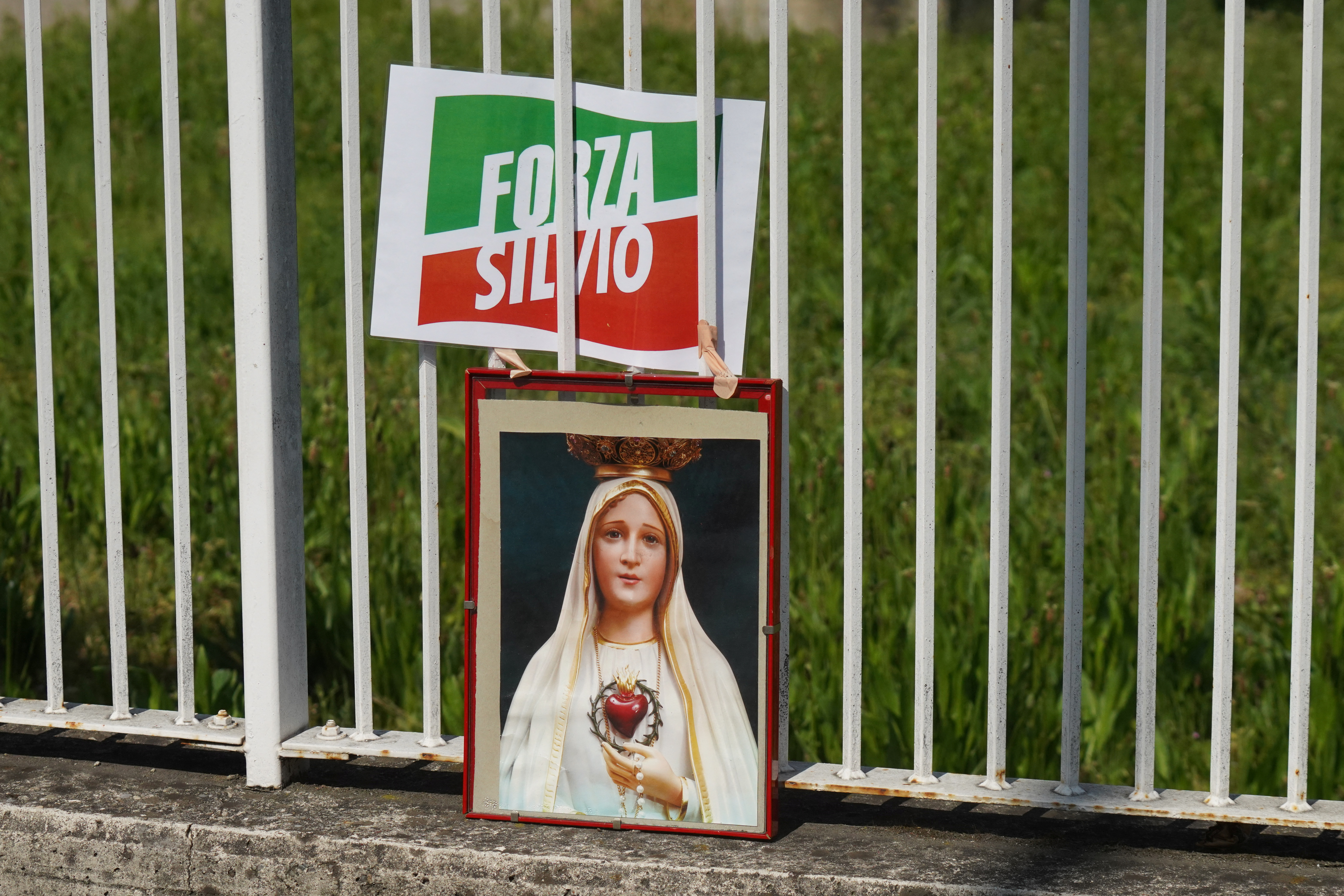 Una imagen de la Virgen acompaña un cartel del partido de Berlusconi en las puertas del hospital (REUTERS/Nicola Marfisi)