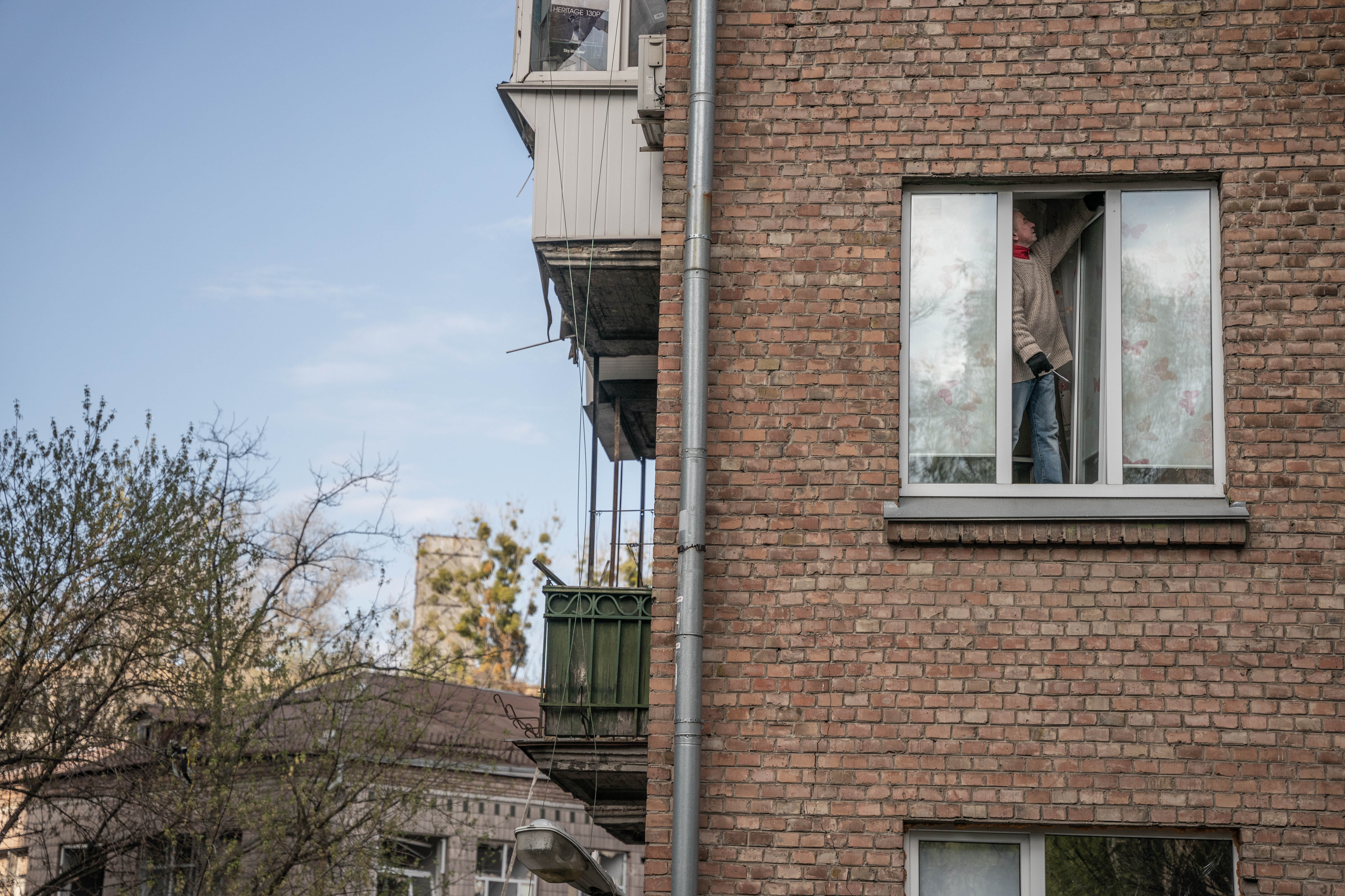 Un vecino hace lo posible por arreglar los restos de una de las ventanas de su departamento.
