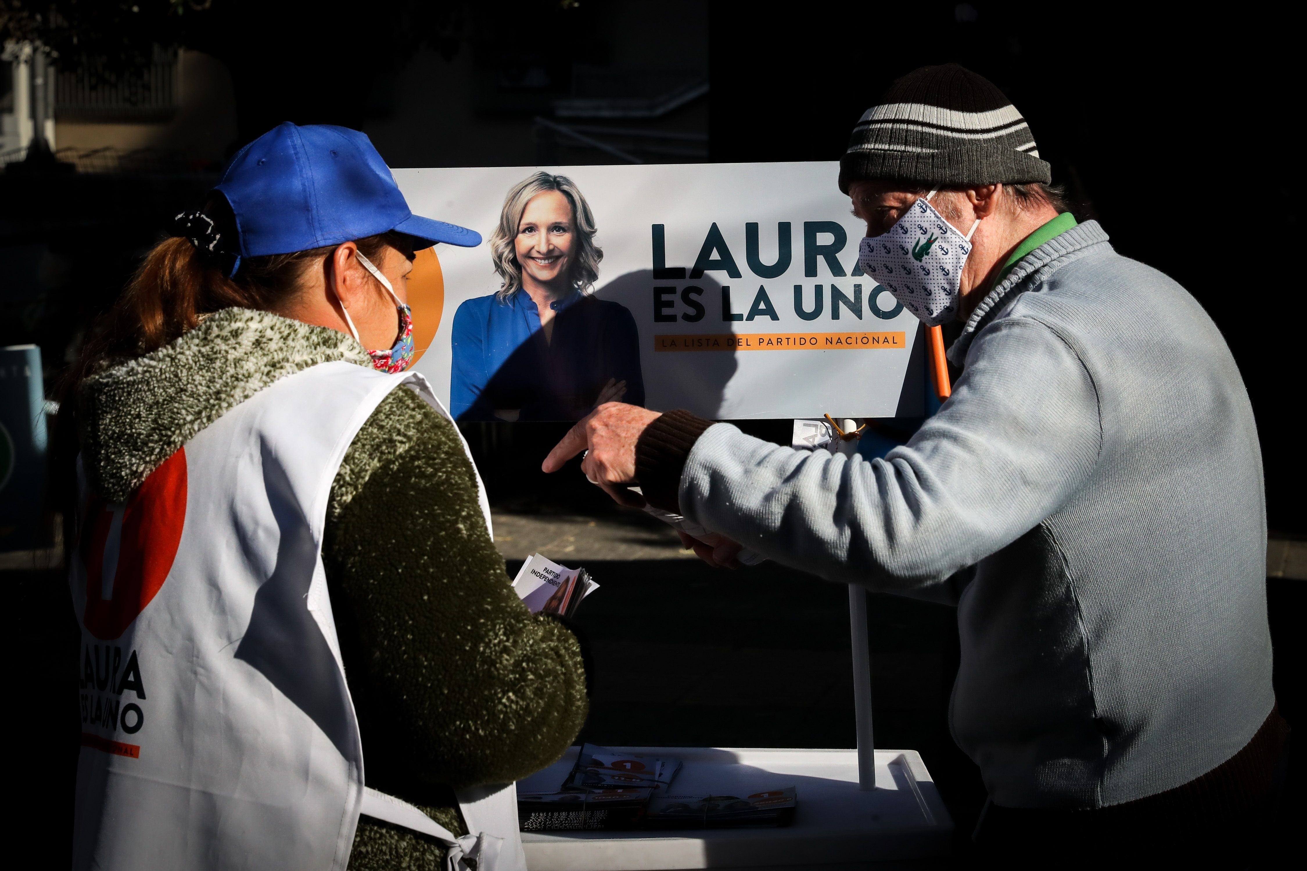 Dos ciudadanos fueron registrados al hablar frente a un afiche de la candidata a la Intendencia de Montevideo Laura Raffo, en Montevideo (Uruguay). EFE/Raúl Martínez