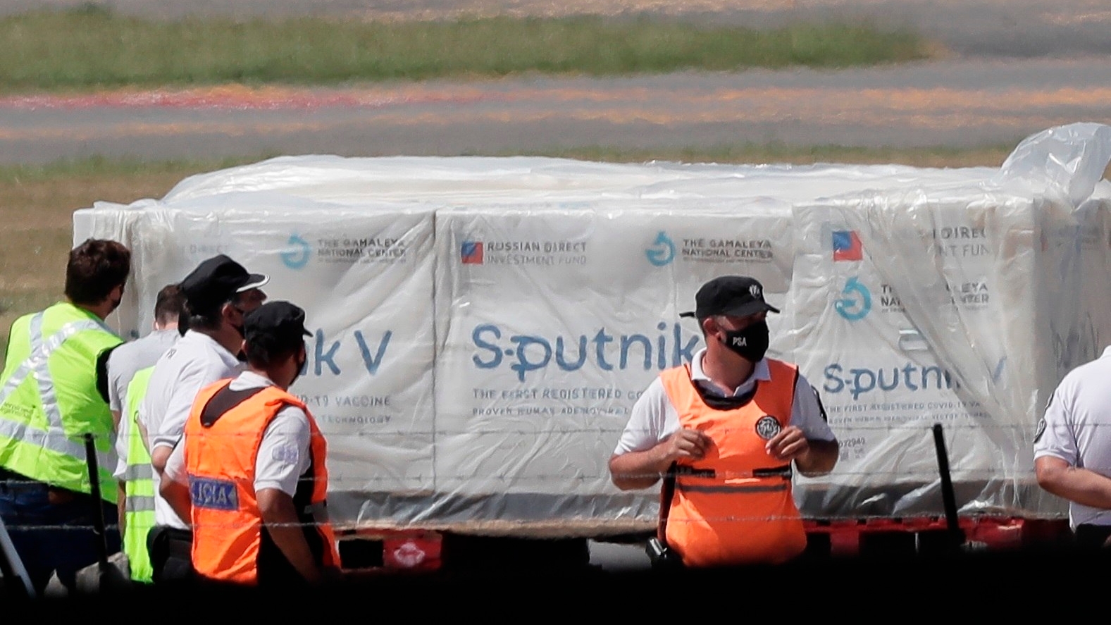 Trabajadores aeroportuarios fueron registrados este jueves al descargar un avión de Aerolíneas Argentinas que trasladó los primeros contenedores de la vacuna rusa Sputnik V contra la covid-19, en el Aeropuerto de Ezeiza en Buenos Aires (Argentina). EFE/Juan Ignacio Roncoroni
